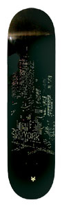 Zoo York Big City Lights skateboard deck: Dark night-time city skyline of lit tower windows in tiny gold dots on a black deck, with ZOO YORK lettering and a small gold logo at the tail.
