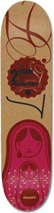 Blueprint Matryos Baker skateboard deck: A red and maroon matryoshka nesting doll with a stylised face and floral detail sits at the bottom of a natural cardboard-brown deck. Above is a red bottle-cap style badge with small text and swirling script lines.