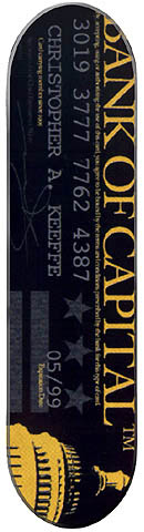 Capital Bank Of Capital skateboard deck: Black deck styled as a bank card, with a gold vertical Bank of Capital title, a long card number, cardholder name, expiry date, three stars and a gold US Capitol dome at the foot.