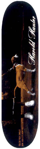 Zoo York Zoo York Harold Hunter skateboard deck: Dark brown photographic deck showing a tan dog on a lead standing on a shadowy street, with white sneakers visible below. 'Harold Hunter' is written in white script down the right side, with small Zoo York text along the left.