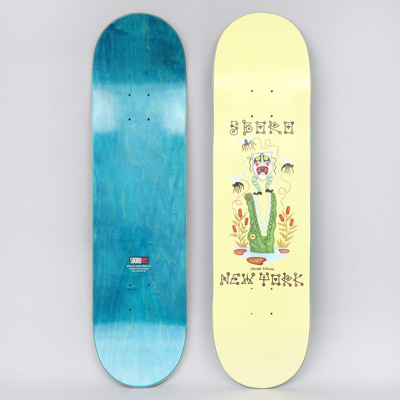 5Boro X Ds 8.25 Jordan Trahan Yellow skateboard deck: A green crocodile with open jaws holds a white-faced mask figure with a striped headdress, swatted at by mosquitoes among cattails. 'Jordan Trahan' appears above lettering reading '5Boro' and 'New York' on a pale yellow deck.
