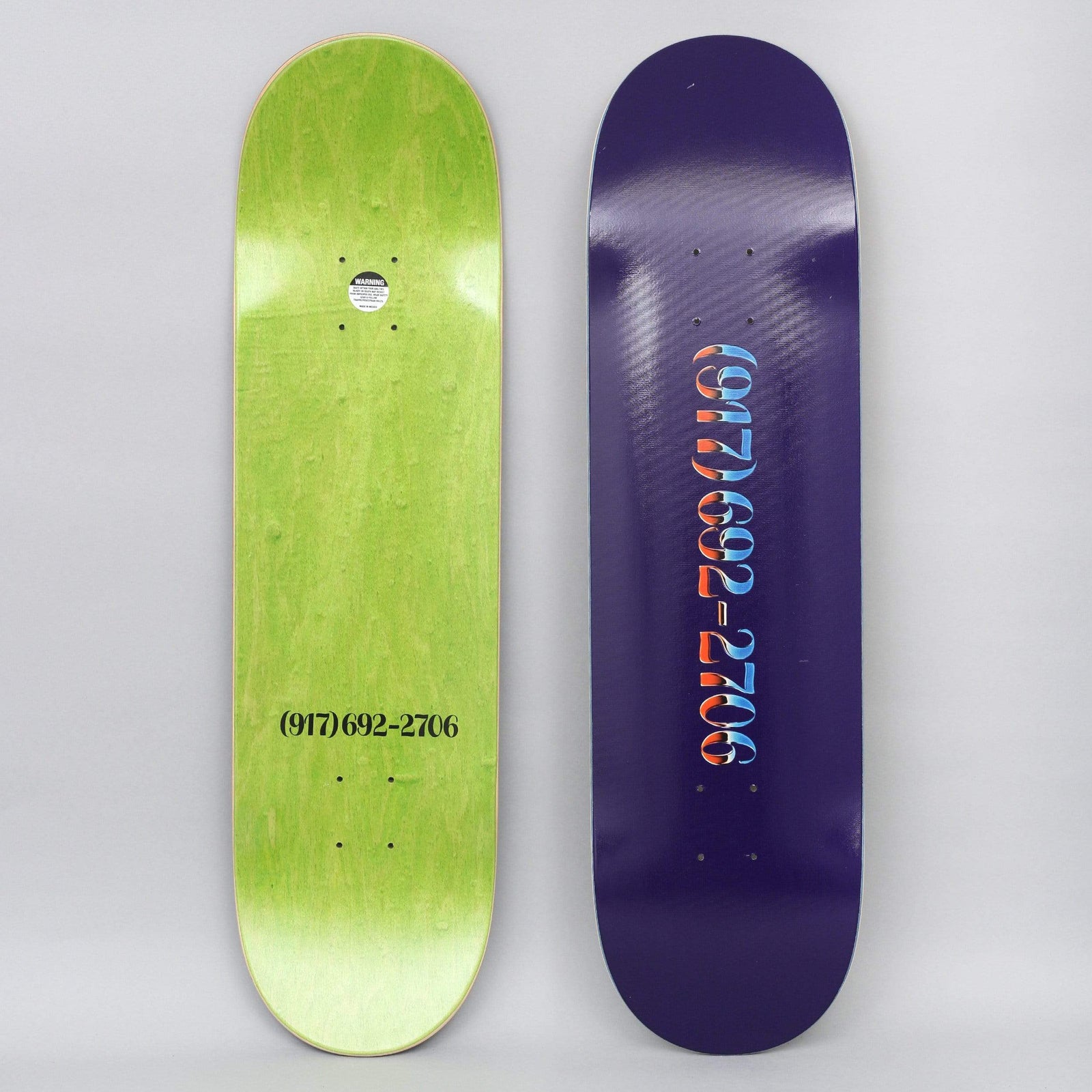 917 17 8.38 Chrome Dialtone Slick Blue skateboard deck: A telephone number in ornate serif numerals with red and blue chrome-style shading on a deep purple deck. The other deck shows the same number in black on a green underside.