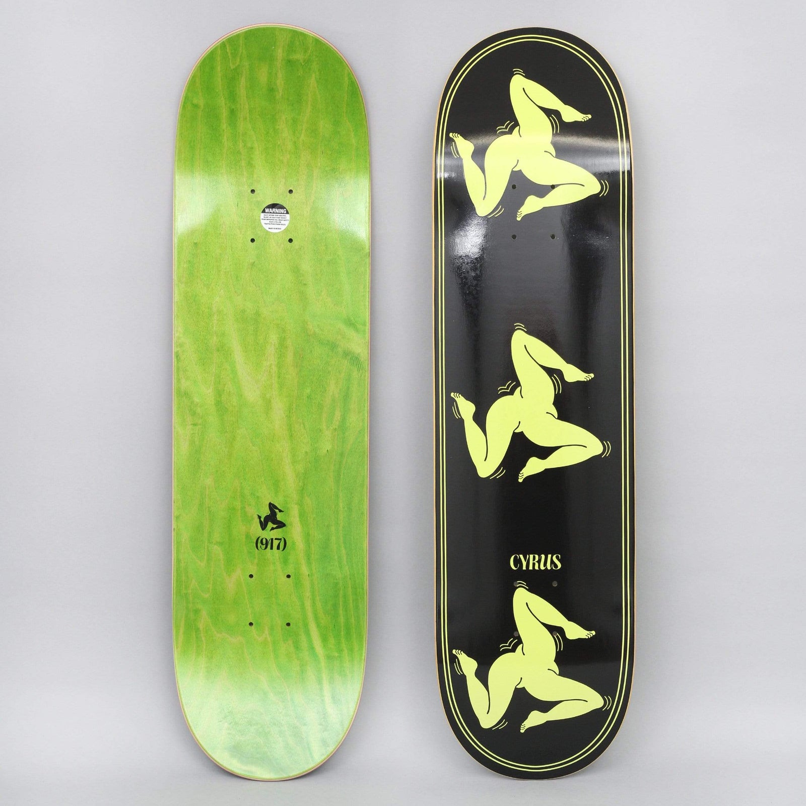 917 17 8.5 Cyrus Legs Black skateboard deck: Black deck with a double pinstripe border and three pale yellow triskelion figures of three bent legs running down the deck, with CYRUS lettering near the tail. The green underside has a small leg logo and (917).