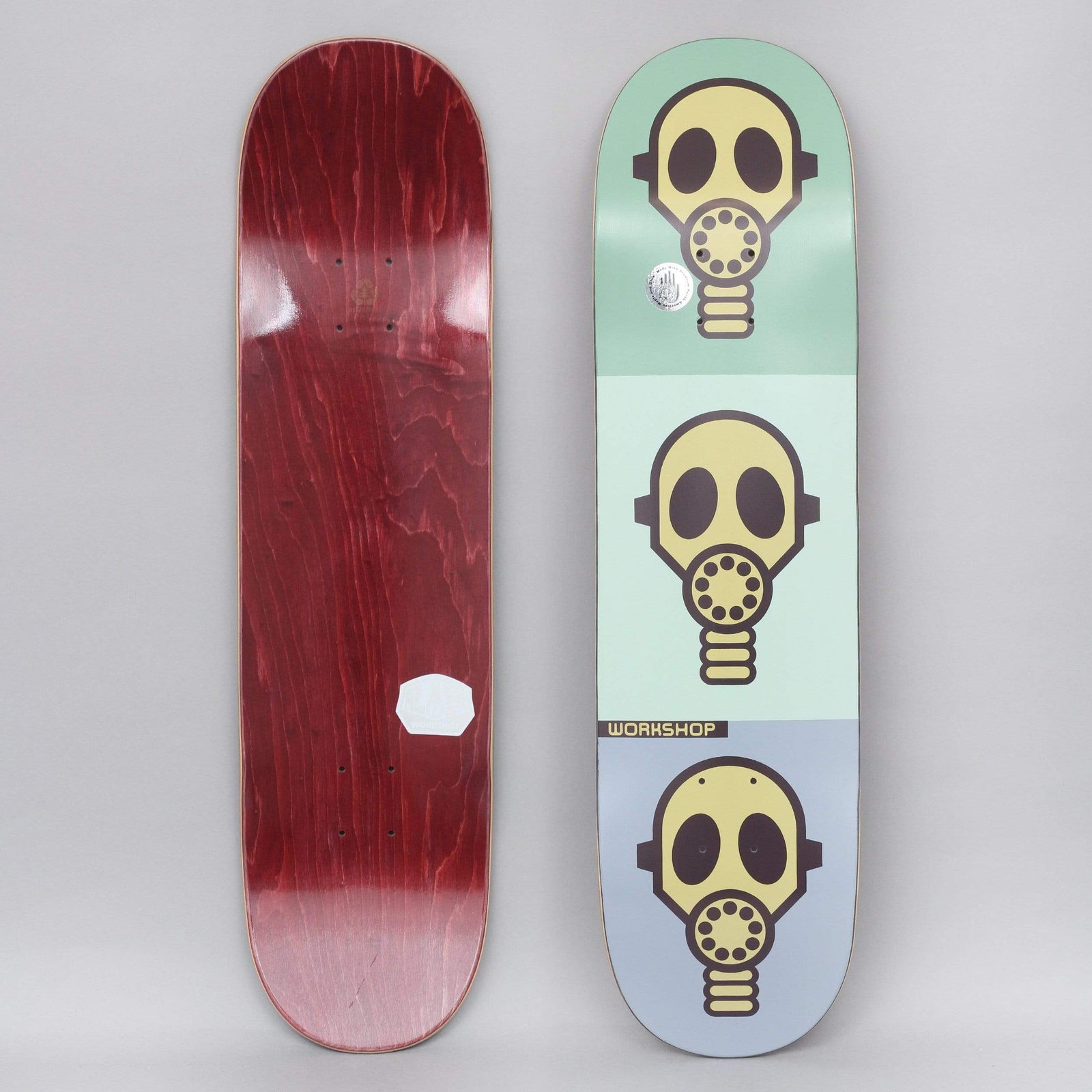 Alien Workshop Gas Mask Pastel skateboard deck: Three yellow gas masks stacked one above the other, each on a pastel green, mint or blue-grey block. A small Workshop label sits at the lower left. The underside is stained dark red.