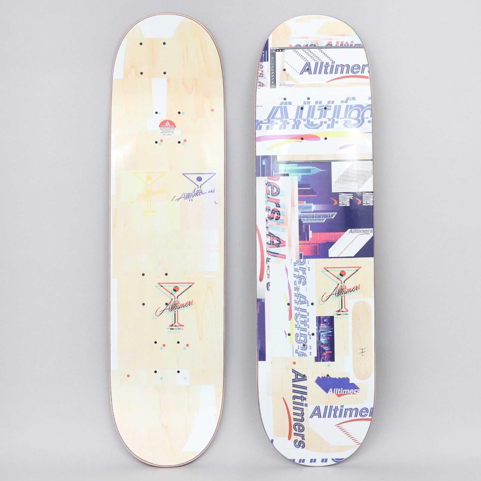 Alltimers Glitch Natural skateboard deck: Both sides shown. The top is a collage of glitchy, overlapping Alltimers logos, cityscape images and martini glass marks in purple, red and cream, on a natural wood deck. The underside carries faint martini glass logos.