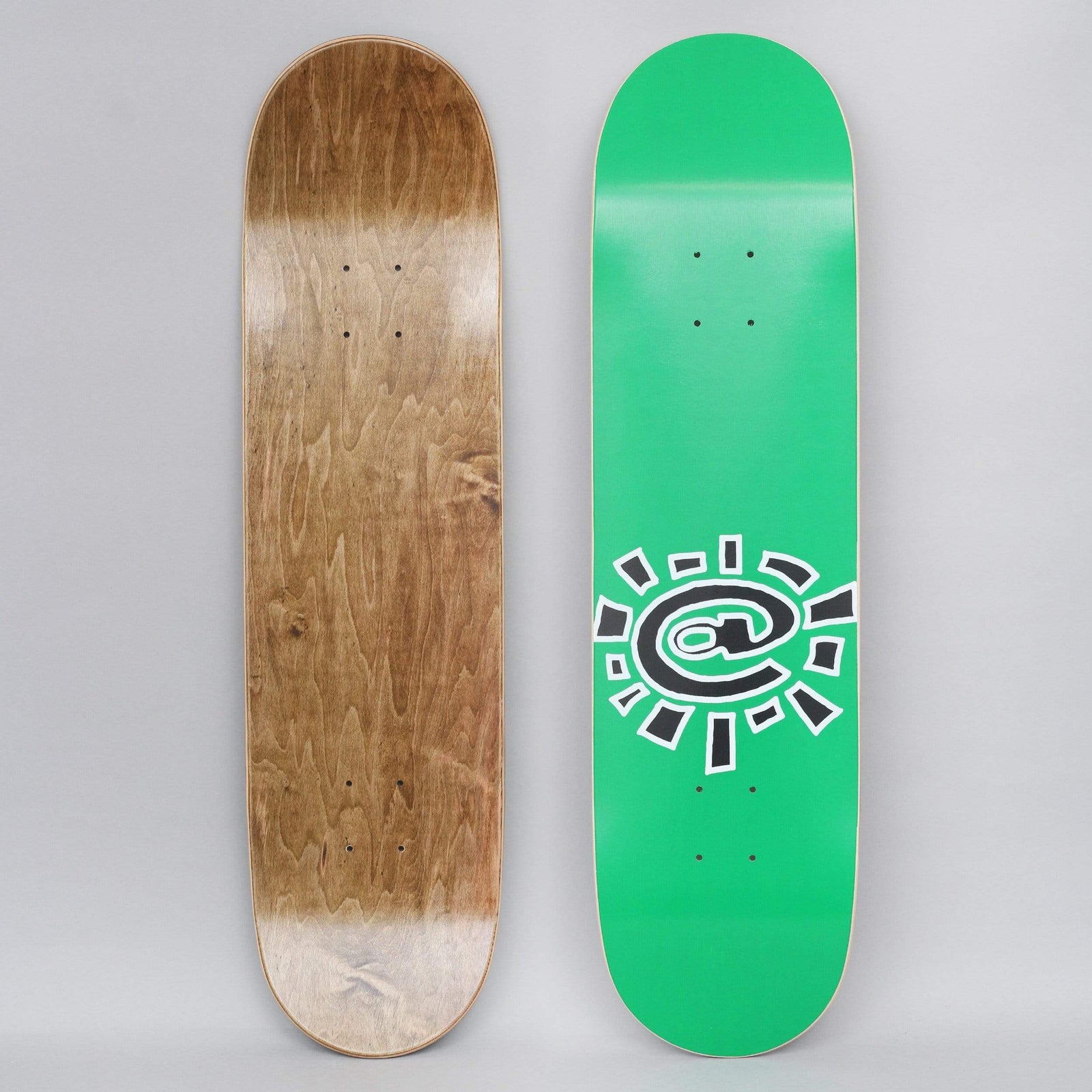 Always @Sun Green skateboard deck: A green deck with a black and white outlined sun made from an @ symbol, with short rays around it. Both the top graphic and the bare wood underside are shown.