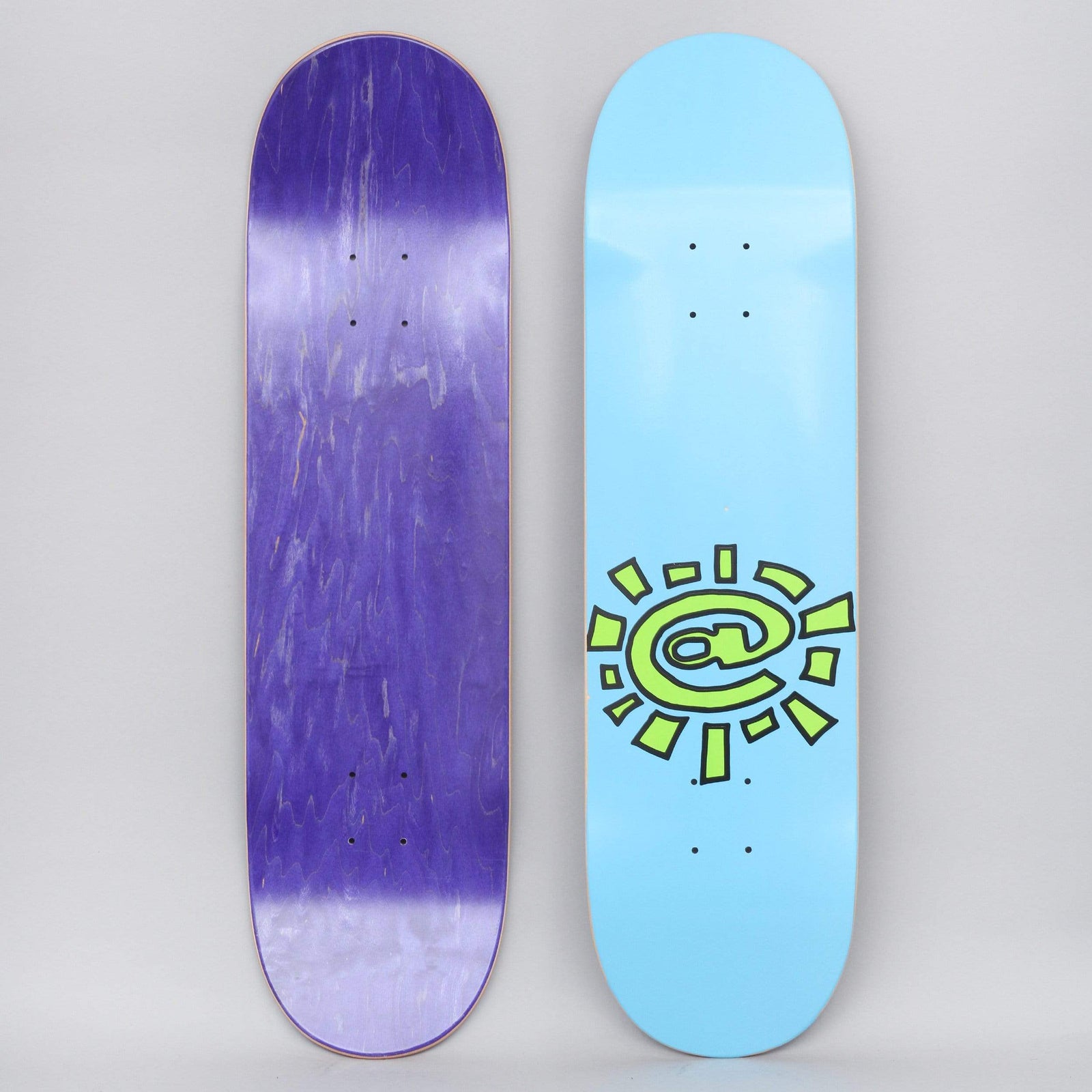 Always @Sun Blue skateboard deck: A lime green sun with an @ symbol at the centre, outlined in black with ragged rays, set low on a plain light blue deck.