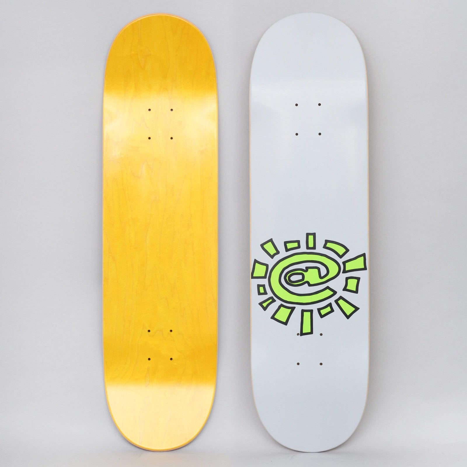 Always @Sun Grey skateboard deck: Light grey deck with a lime green sun made from an at symbol with chunky rays and black outlines, placed low on the deck. Underside shows a plain yellow stain.