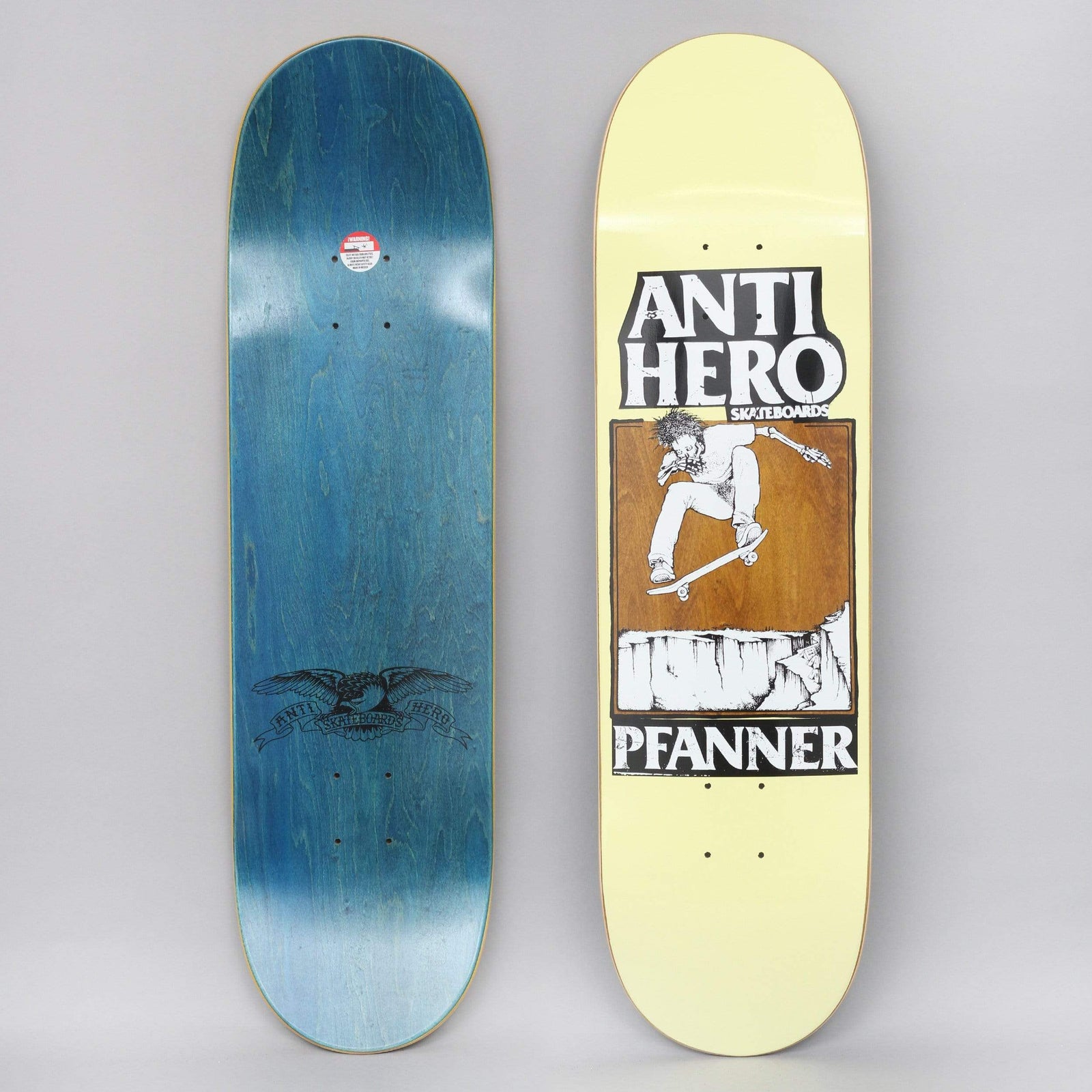 Anti Hero Pfanner Lance Yellow / Brown skateboard deck: Black and white pen drawing of a skater flipping the board above a cliff edge, set in a brown panel under bold Anti Hero lettering with the rider's name below. Pale yellow deck; the underside shows the eagle logo on blue.