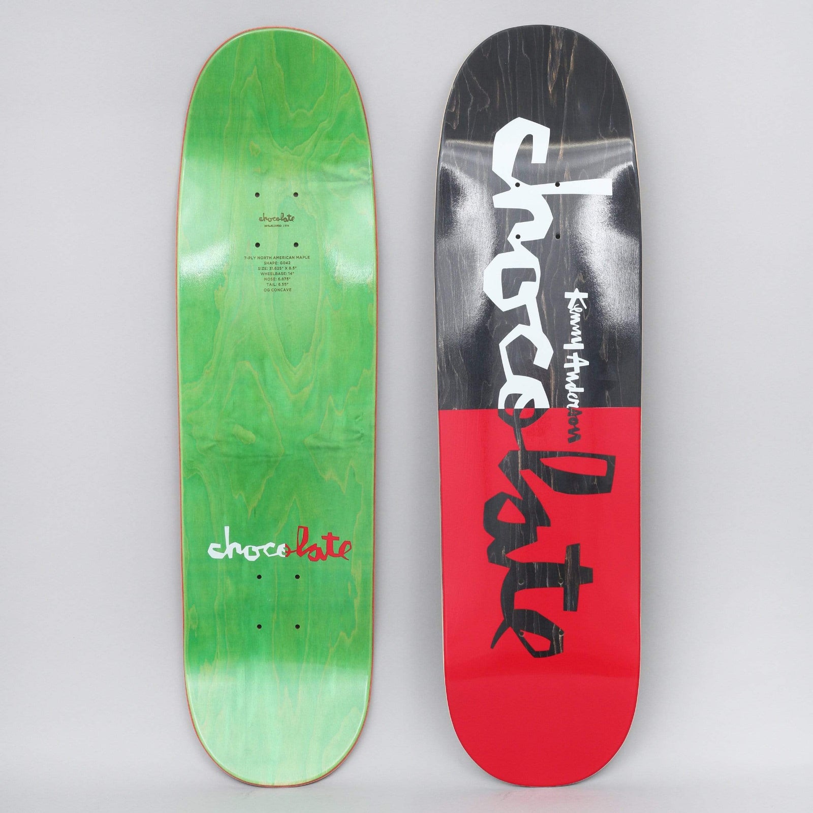 Chocolate Kenny Anderson Original Chunk Black / Red skateboard deck: A deck split into a black top half and a red bottom half, with large white and black brush-style Chocolate lettering running down it and the rider name in small white script. The underside is green with a small logo.