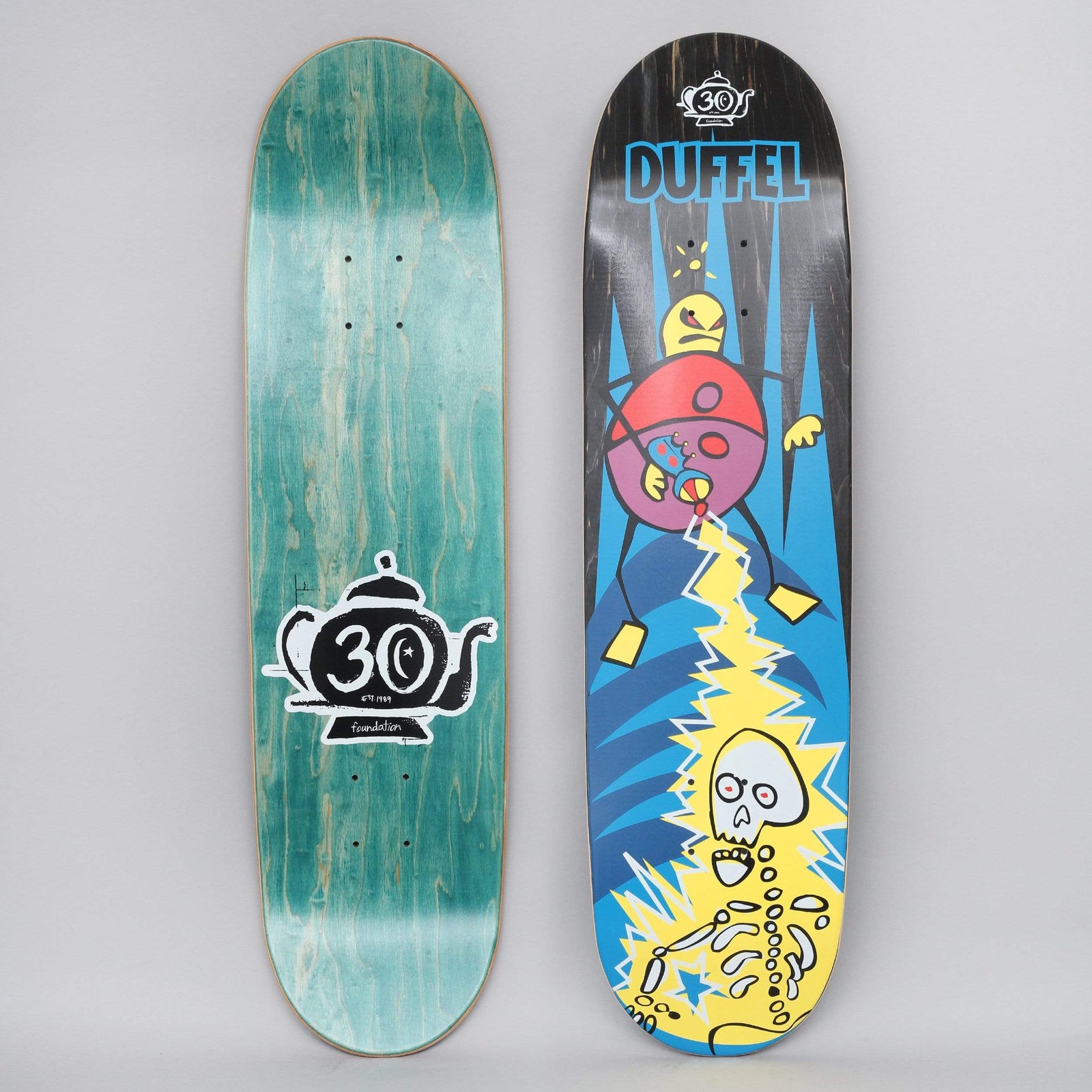 Foundation Duffel Phaser skateboard deck: Cartoon of a round purple and red creature with a yellow head zapping a yellow-outlined skeleton with a lightning bolt against a blue spiky background. Duffel name in blue at the top with a 30th anniversary teapot logo; bottom view shows teal stain with a large teapot logo.