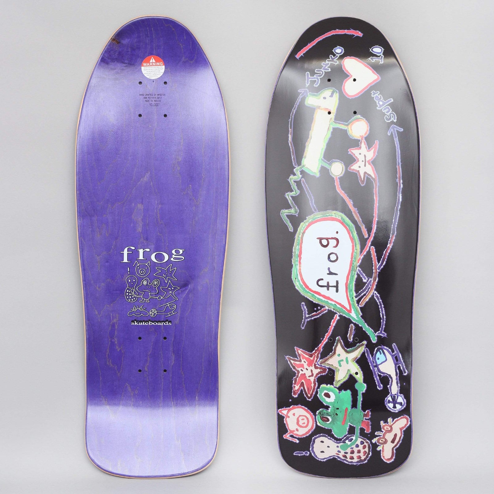 Frog Super Junko Black skateboard deck: Childlike crayon-style drawing on black of a skateboard with a speech bubble reading frog, a green frog, stars, a heart, a helicopter and small animals. Purple underside shows the frog skateboards logo with doodles.