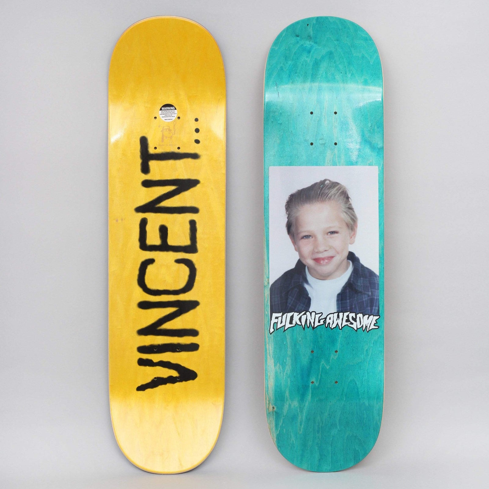 Fucking Awesome Vincent Class Photo skateboard deck: School-style photograph of a smiling young boy with slicked-back blond hair in a checked shirt, with the Fucking Awesome logo beneath on a teal-stained deck. The yellow underside has the name Vincent in black spray lettering.