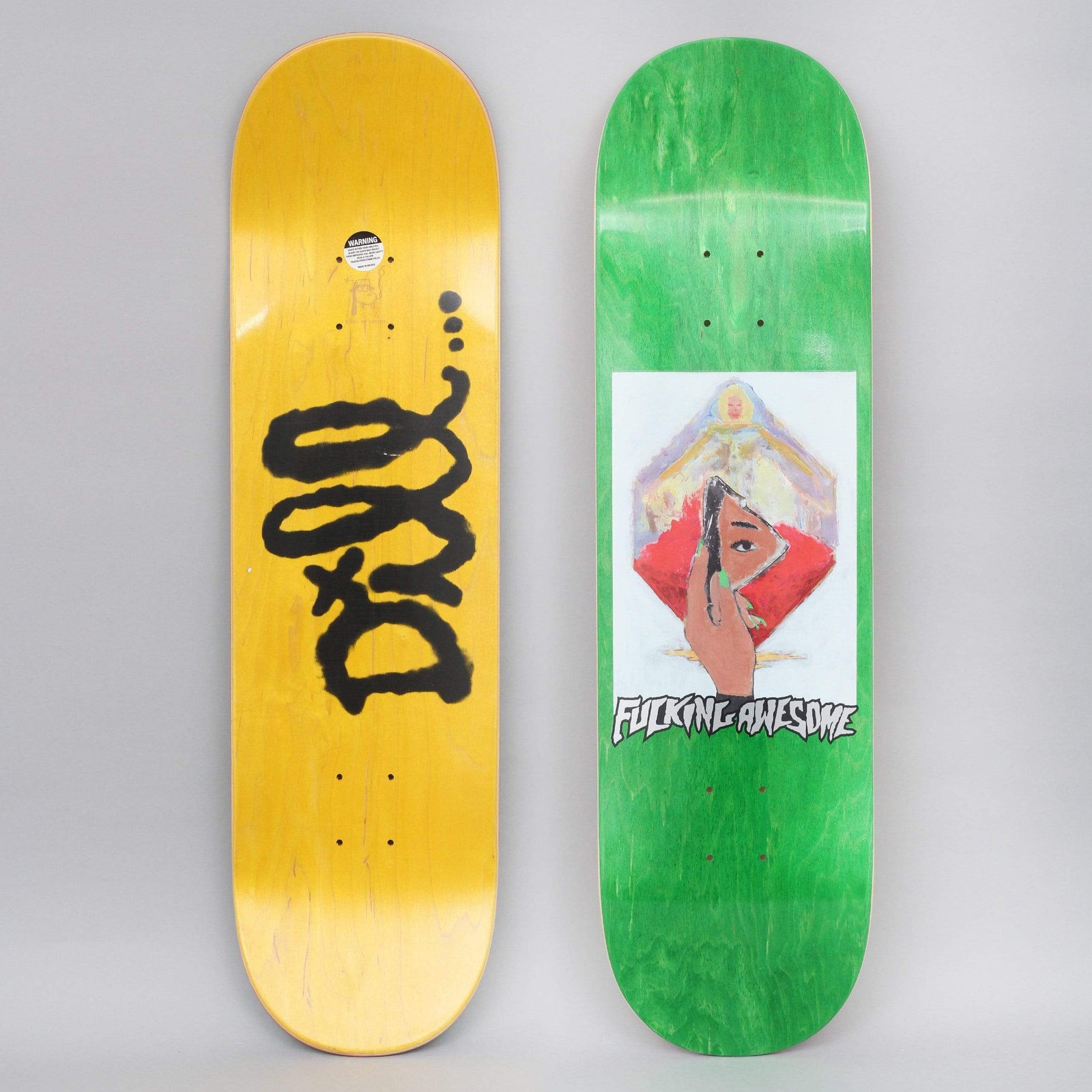 Fucking Awesome Dill Mirror Painting skateboard deck: Painted artwork of a hand holding a small mirror reflecting an eye, in front of a red diamond and a radiant figure, framed in a white panel on green. The other deck has a black spray-paint scrawl on yellow.