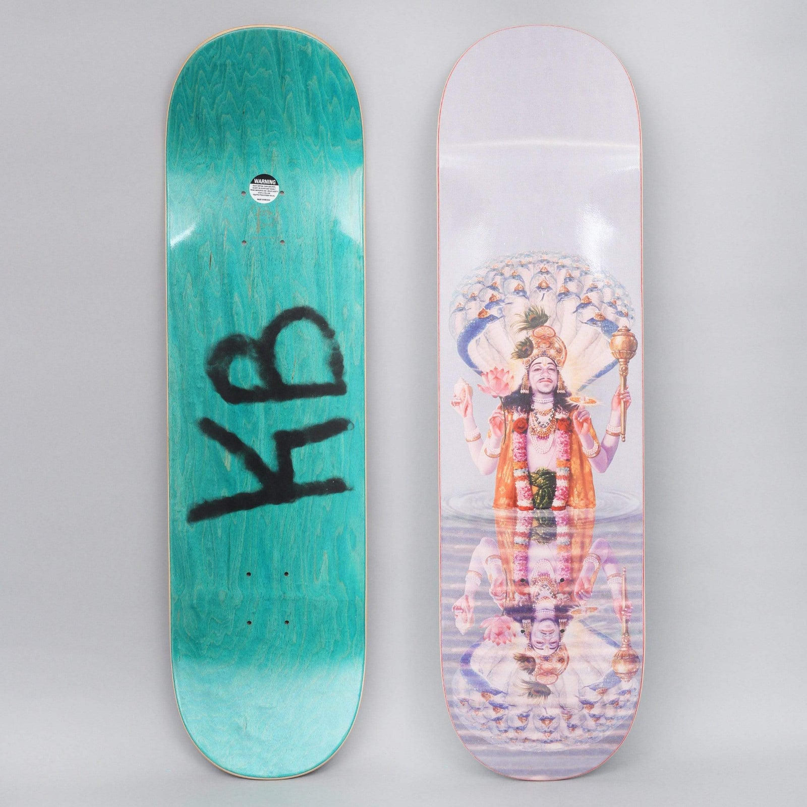Fucking Awesome Kevin Bradley Ganesh skateboard deck: Painting-style image of a multi-armed deity under a many-headed serpent canopy, standing in water with a mirrored reflection below, on a pale lilac ground. The base is stained green with a black KB tag; both sides shown.