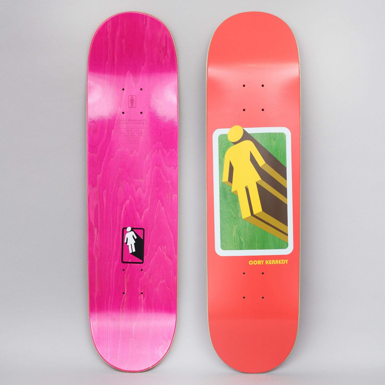 Girl Cory Kennedy 3D OG Red skateboard deck: Red deck with a yellow Girl logo figure casting a long extruded brown shadow, framed in a rounded white-bordered panel on green. Rider name beneath. The photo also shows the pink-stained underside with a small logo.