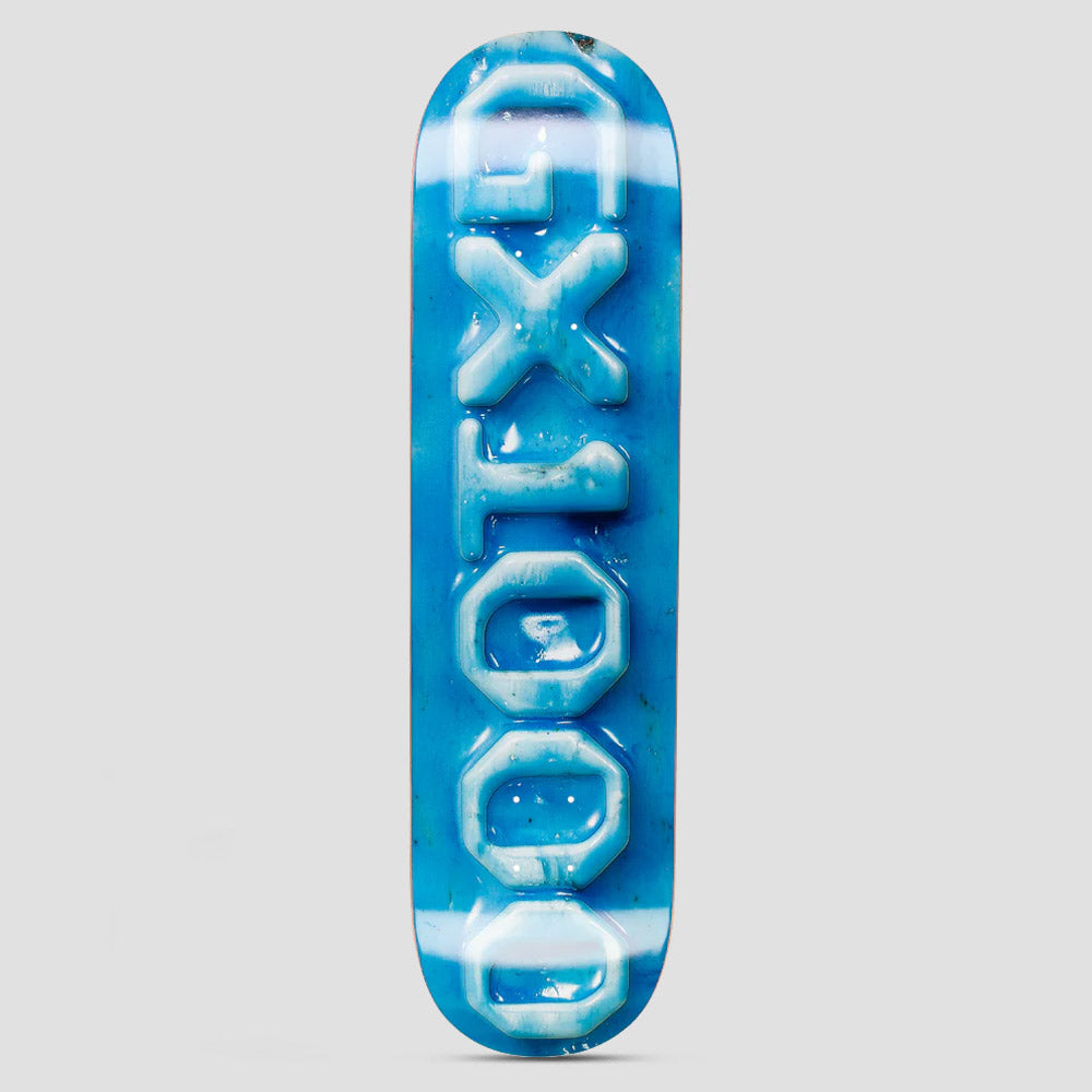GX1000 Ceramic OG Logo Blue skateboard deck: Large vertical GX1000 logo letters rendered as a glossy, raised ceramic-look relief in pale blue, on a mottled bright blue background with white streaks.