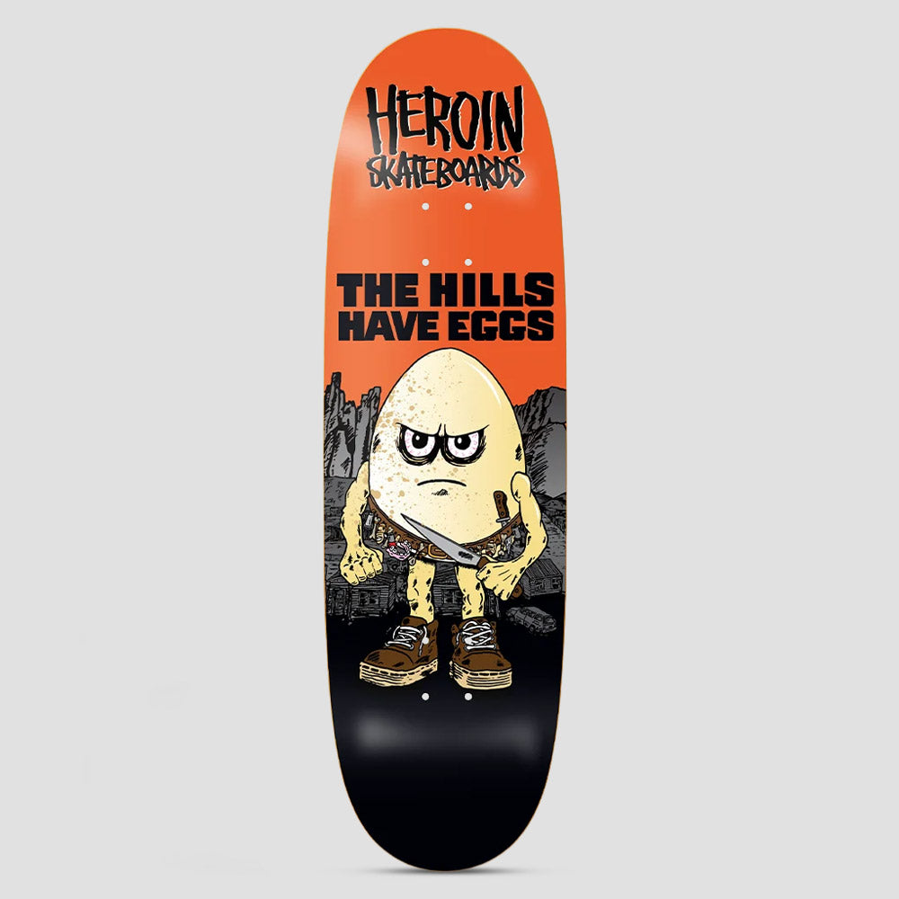 Heroin Hills Have Eggs skateboard deck: Scowling cartoon egg in brown boots with a knife in its belt, standing before rocky hills and ramshackle buildings. Heroin Skateboards logo and 'The Hills Have Eggs' at the top on orange, fading to black.