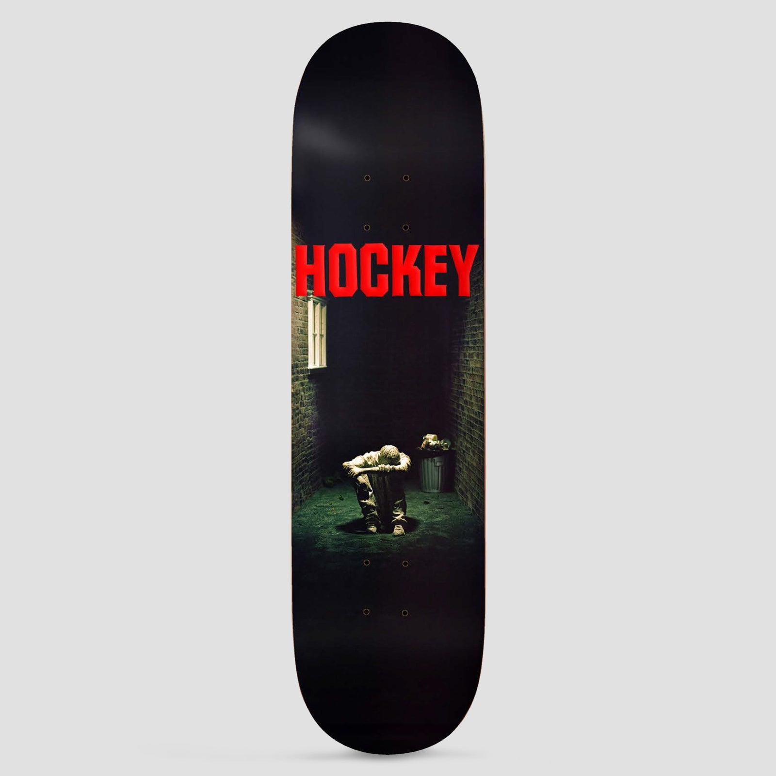 Hockey Still Missing Shape 1 skateboard deck: Dark photographic scene of a hooded figure crouched head-down in a brick alley, with a lit window, a bin and an open manhole. Large red 'HOCKEY' lettering across the top.