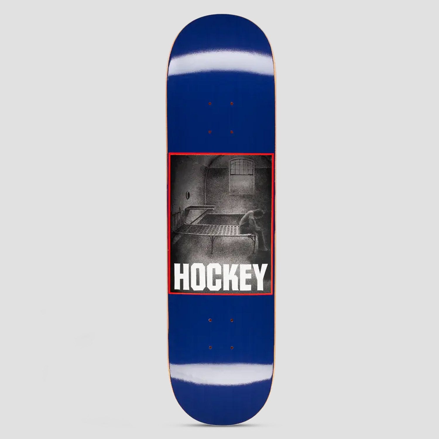 Hockey Bed Rot John Fitzgerald Shape 2 skateboard deck: A black and white photograph in a red frame shows a person slumped on the edge of a metal bed in a bare cell-like room with a barred window. The Hockey logo is in white block capitals below, on a deep blue deck.