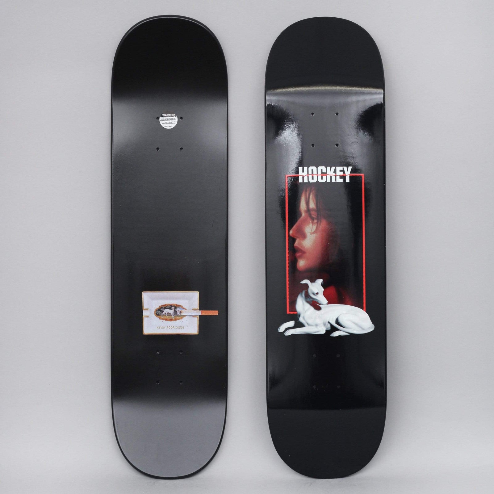Hockey Kevin Rodriguez Greyhound Black skateboard deck: A black deck with the Hockey logo above a red-framed photo of a woman's profile, with a white greyhound lying below. The underside has a small ashtray with a cigarette and the rider name.