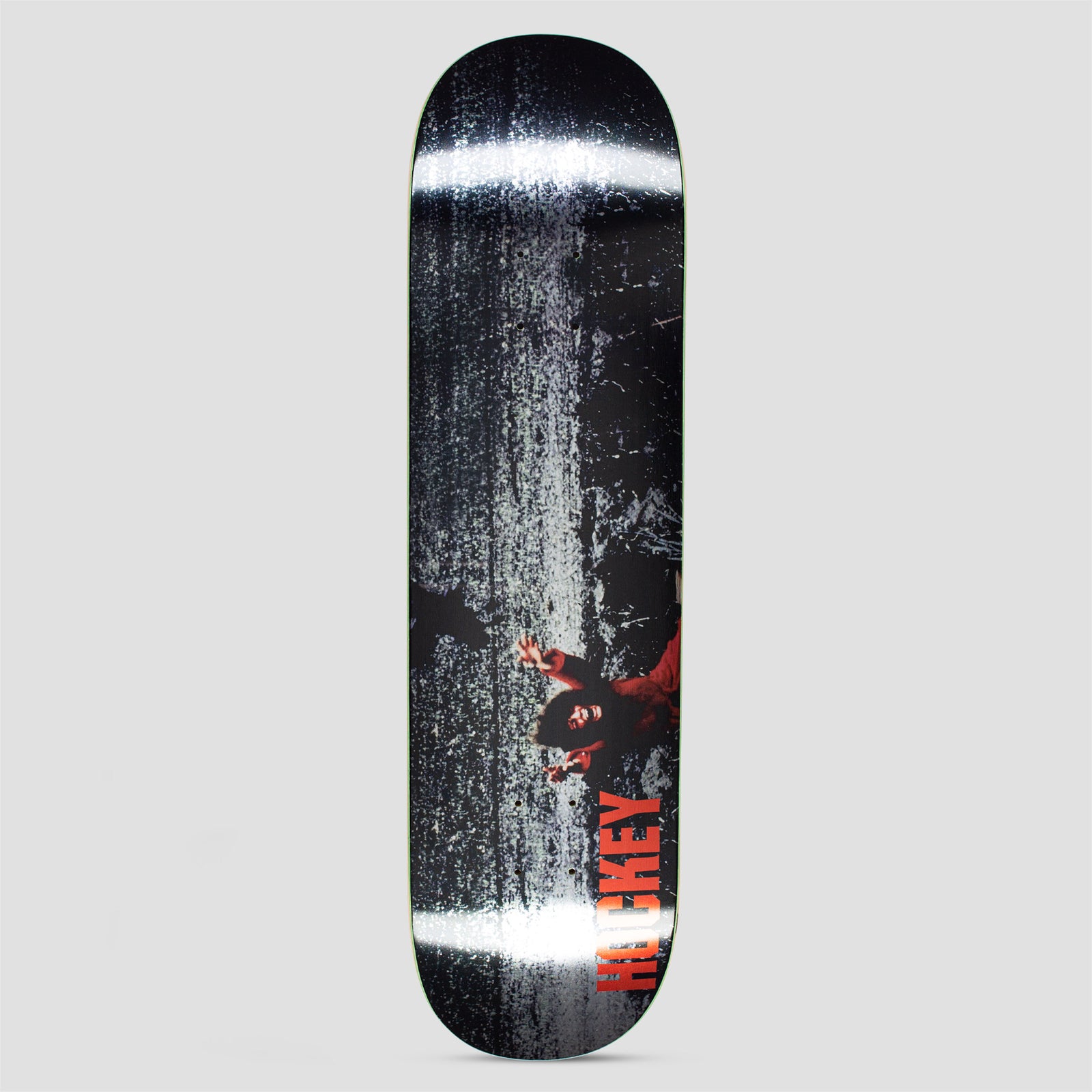 Hockey Kevin Rodrigues Prey skateboard deck: Dark, grainy black and white texture with two bright horizontal glare bands. A small figure in red with arms outstretched lies low on the right, with Hockey in red capitals running up the lower edge.
