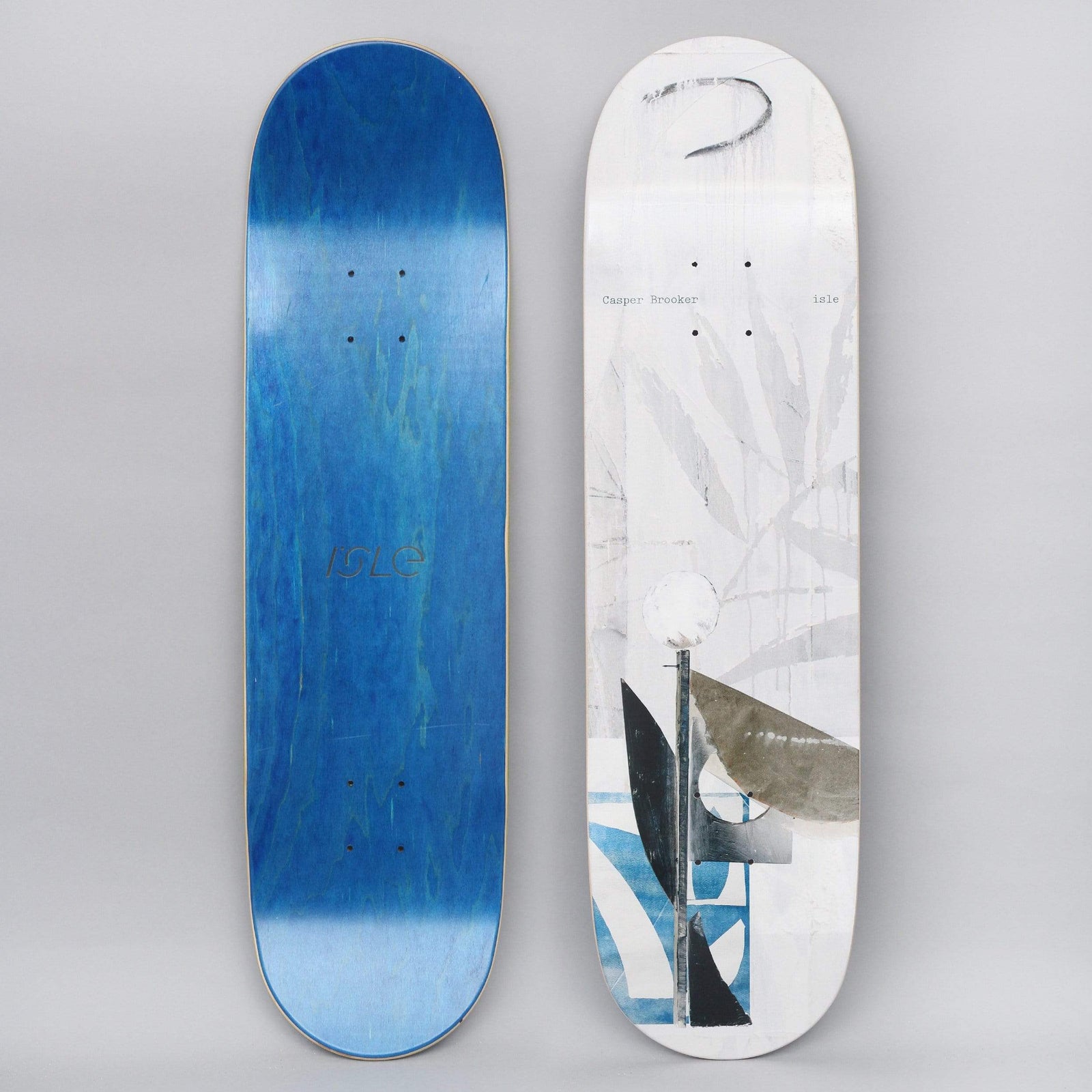 Isle Brooker Sculpture Series skateboard deck: A white deck with a muted collage-style image of a lamppost and curved sculptural shapes in black, grey and blue, over faint leaf shapes and a scrawled mark. Small typed names sit at the top. The other side is blue.