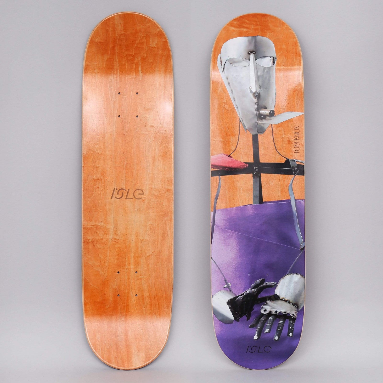 Isle Knox Kira Freije Artist Series Orange skateboard deck: Photographic collage of a metal sculpture figure with a riveted steel mask and plate hands, against an orange background with a purple area below. Artist name printed on the right and the logo at the bottom.