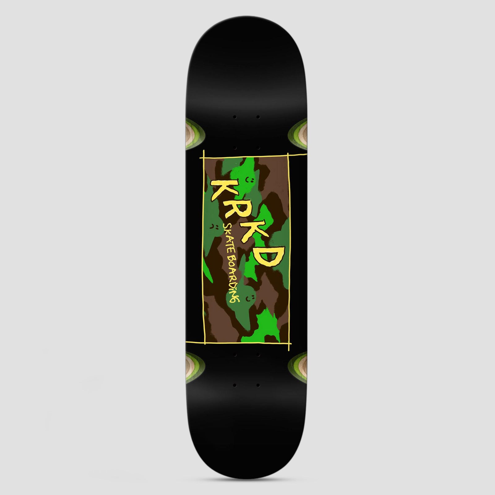 Krooked KR Kamo Wheel Wells Black skateboard deck: Black deck with a hand-drawn yellow-bordered rectangle of green and brown camouflage with tiny faces, and KRKD Skate Boarding lettering in yellow. Wood-coloured wheel-well circles at the corners.