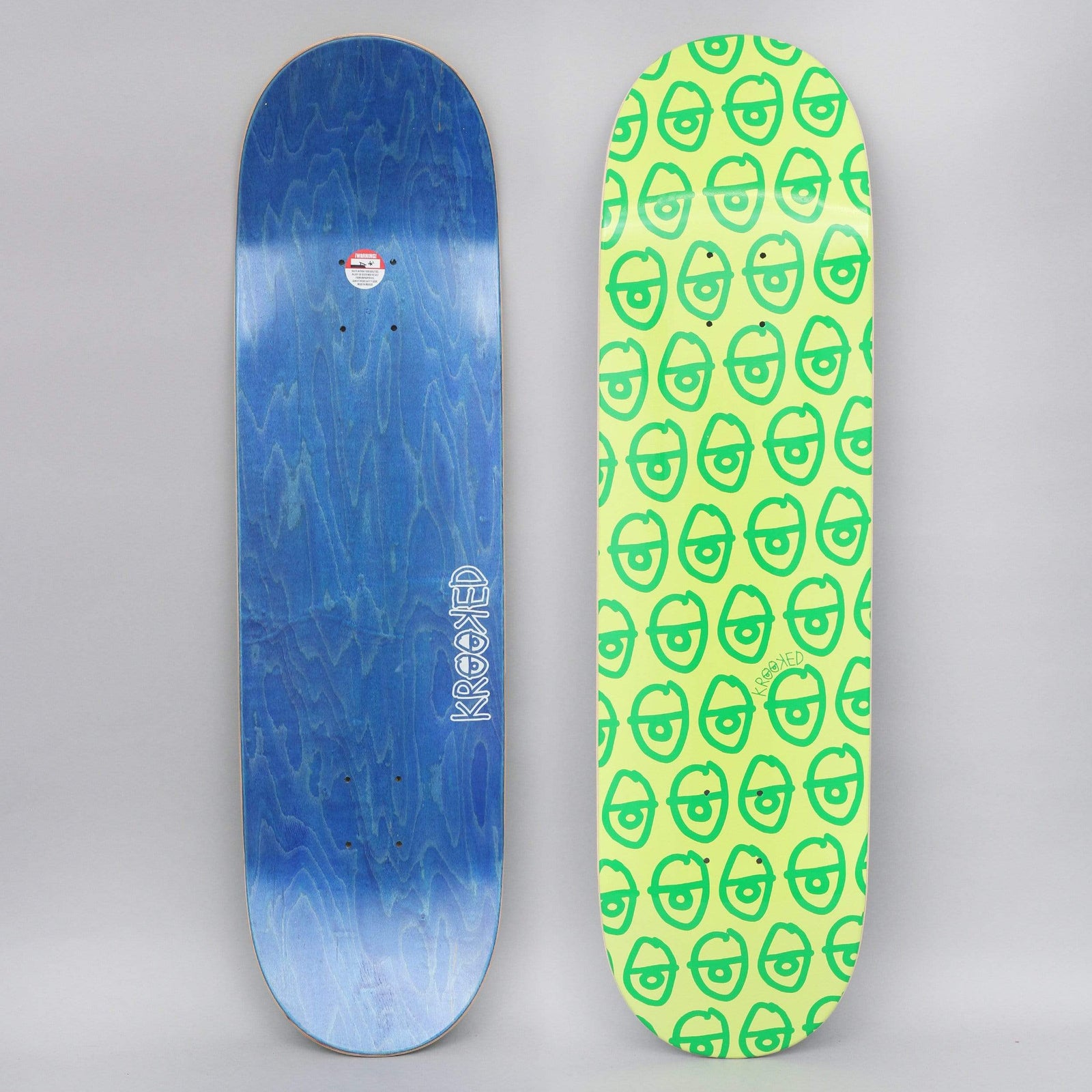 Krooked Pewpils Green skateboard deck: A repeating pattern of small green cartoon heads with single large eyes covers a lime green deck. The photo shows the top and a blue-stained underside with the Krooked logo.