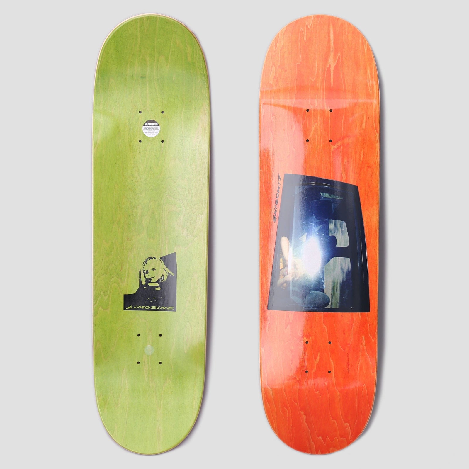 Limosine Cyrus Bennett Window Orange skateboard deck: Photograph of a car window with a bright flash glare and blurred shapes inside, on an orange-stained deck with small vertical brand name. Underside is green with a black print of a child's face in a window.