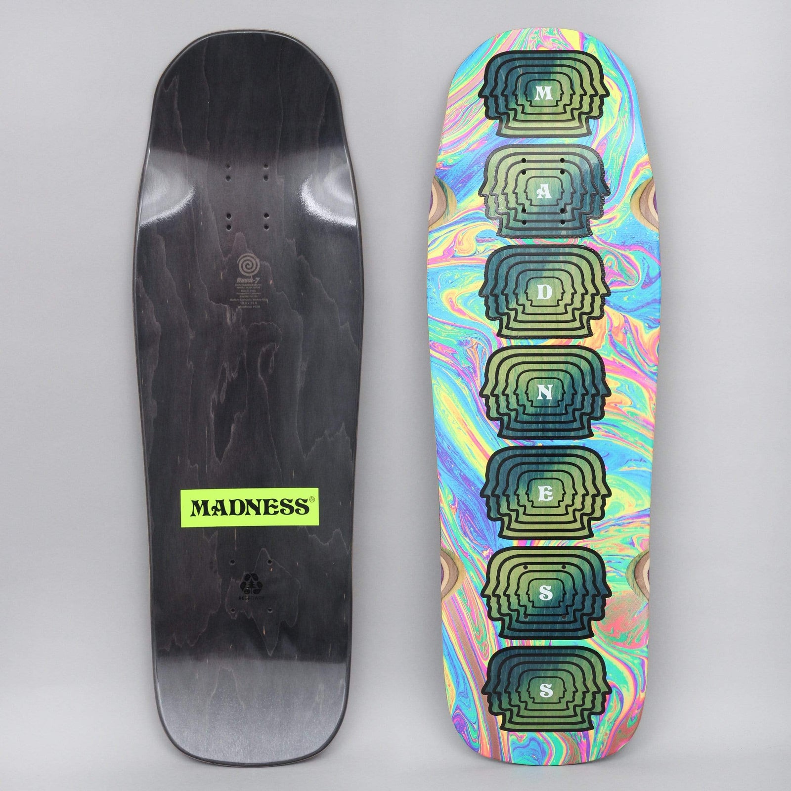Madness Mental skateboard deck: Old-school shaped deck with a swirling rainbow oil-slick background and a column of seven stacked head silhouettes, each carrying one letter of the brand name. The black underside has a neon yellow Madness label.