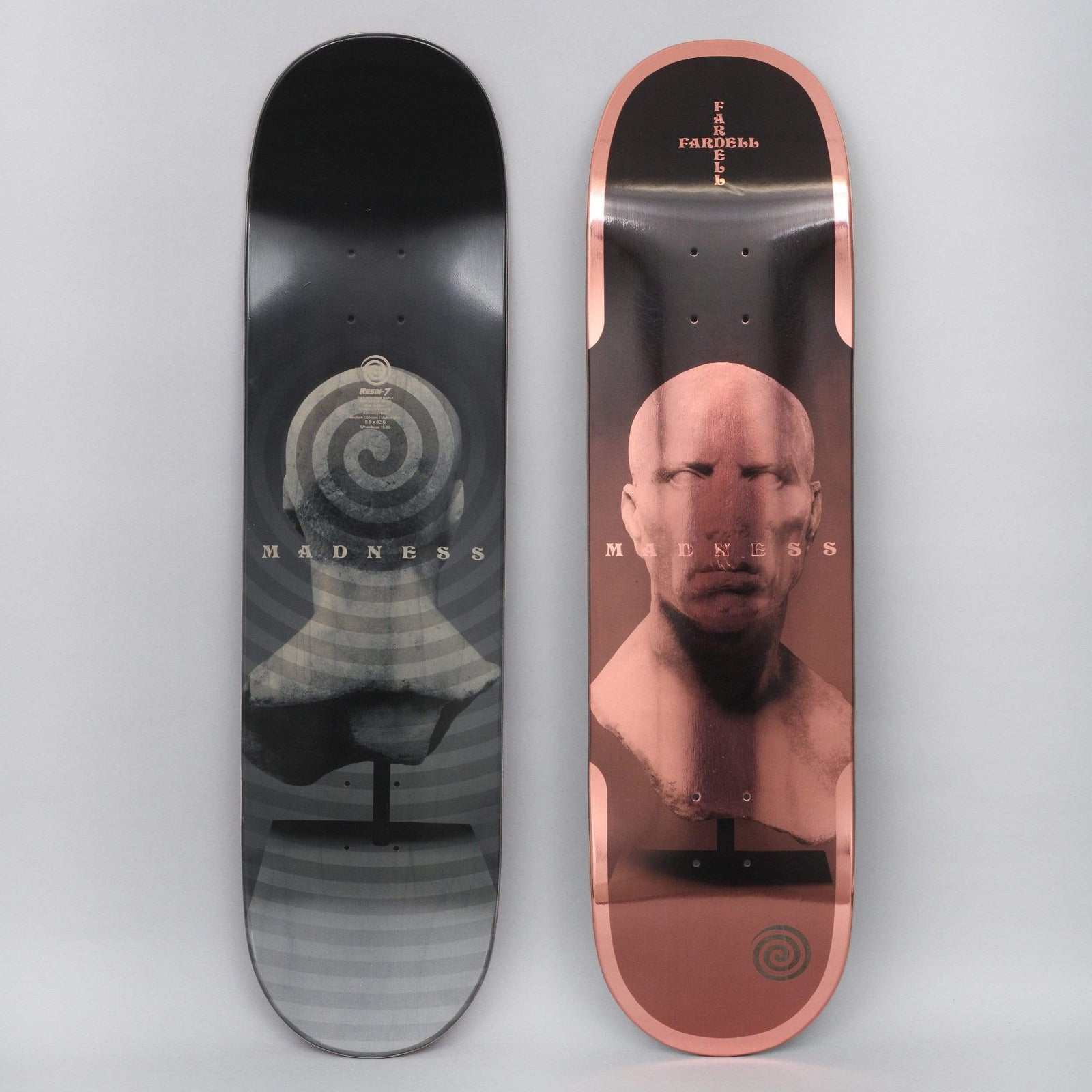 Madness Jack Fardell Trauma Bronze skateboard deck: Classical bust of a bald male head on a stand, with a spiral on the back of the head in the black version and a rose-copper metallic foil finish with a small spiral logo on the other. Photo shows two decks.