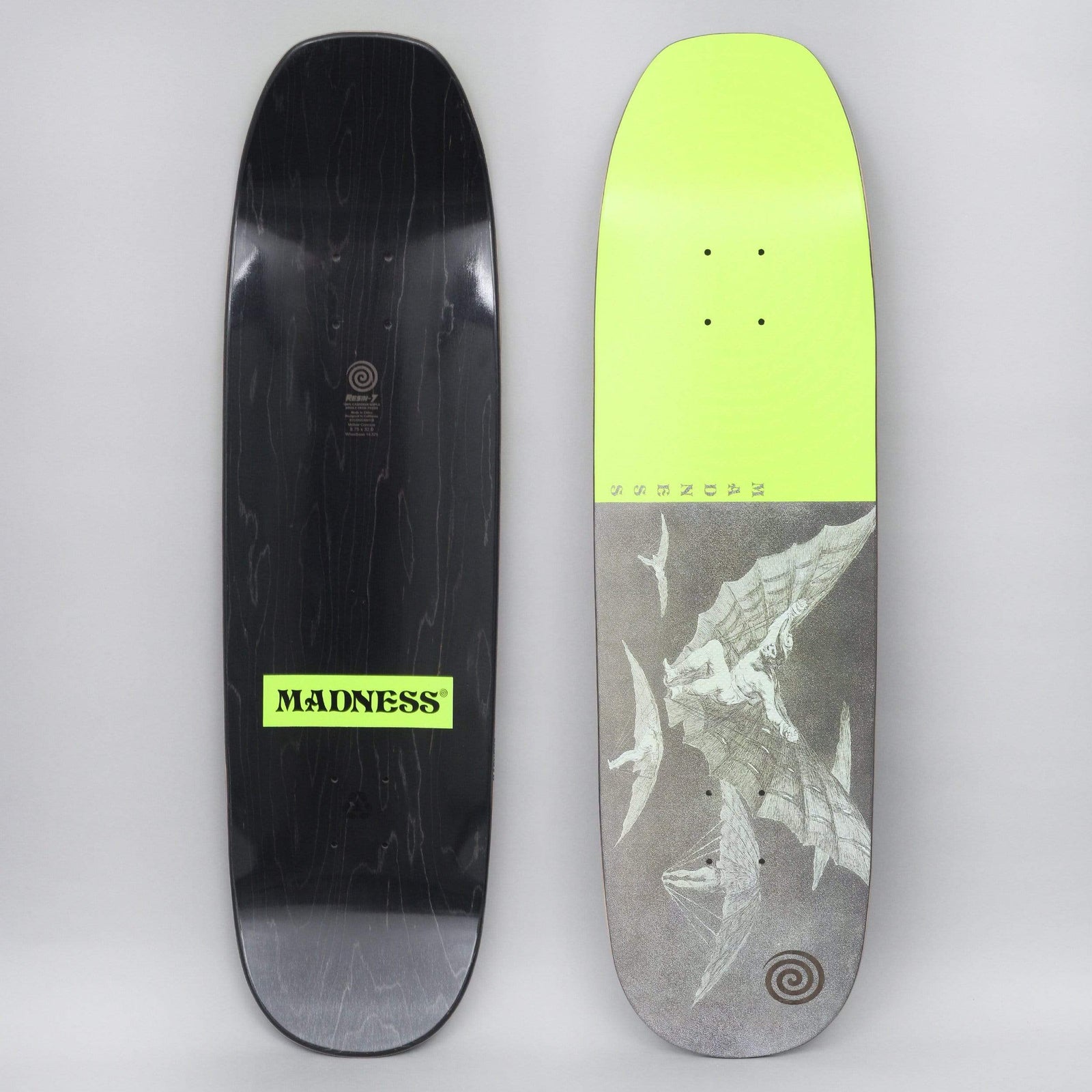 Madness Flight Neon Yellow skateboard deck: Shaped deck with the top half solid neon yellow and the lower half grey, showing a pale engraving of a winged flying machine with bat-like wings. Small spiral logo at the tail and vertical 'MADNESS' lettering at the split.