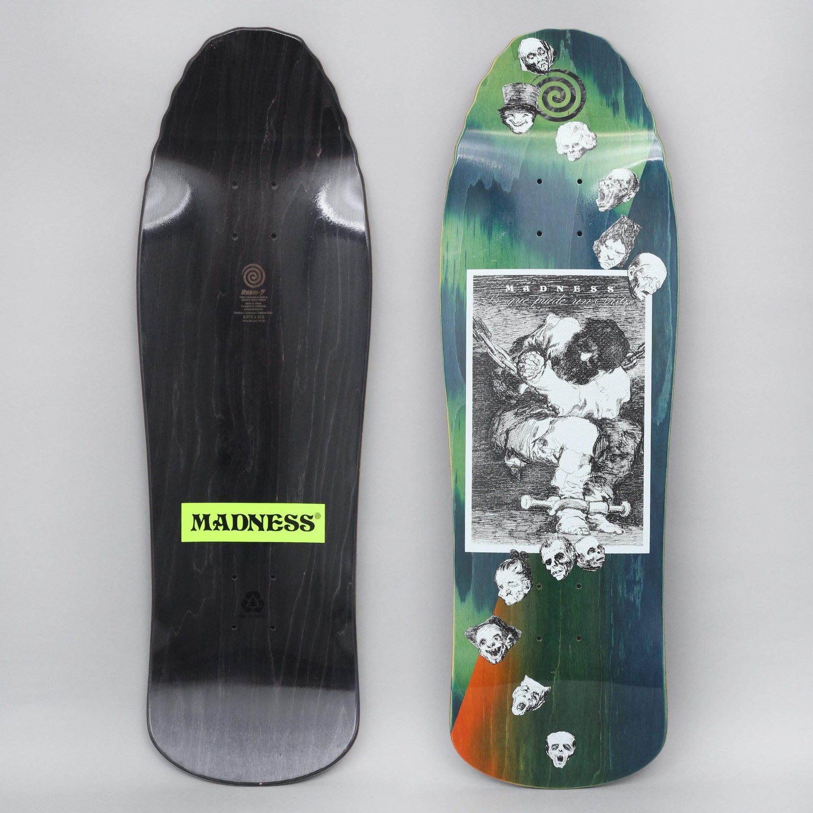Madness Captivity skateboard deck: Black and white etching of a hooded figure chained and slumped, framed in a white panel, surrounded by a trail of grotesque skull and mask heads and a spiral, on a green, blue and orange stained shaped deck.