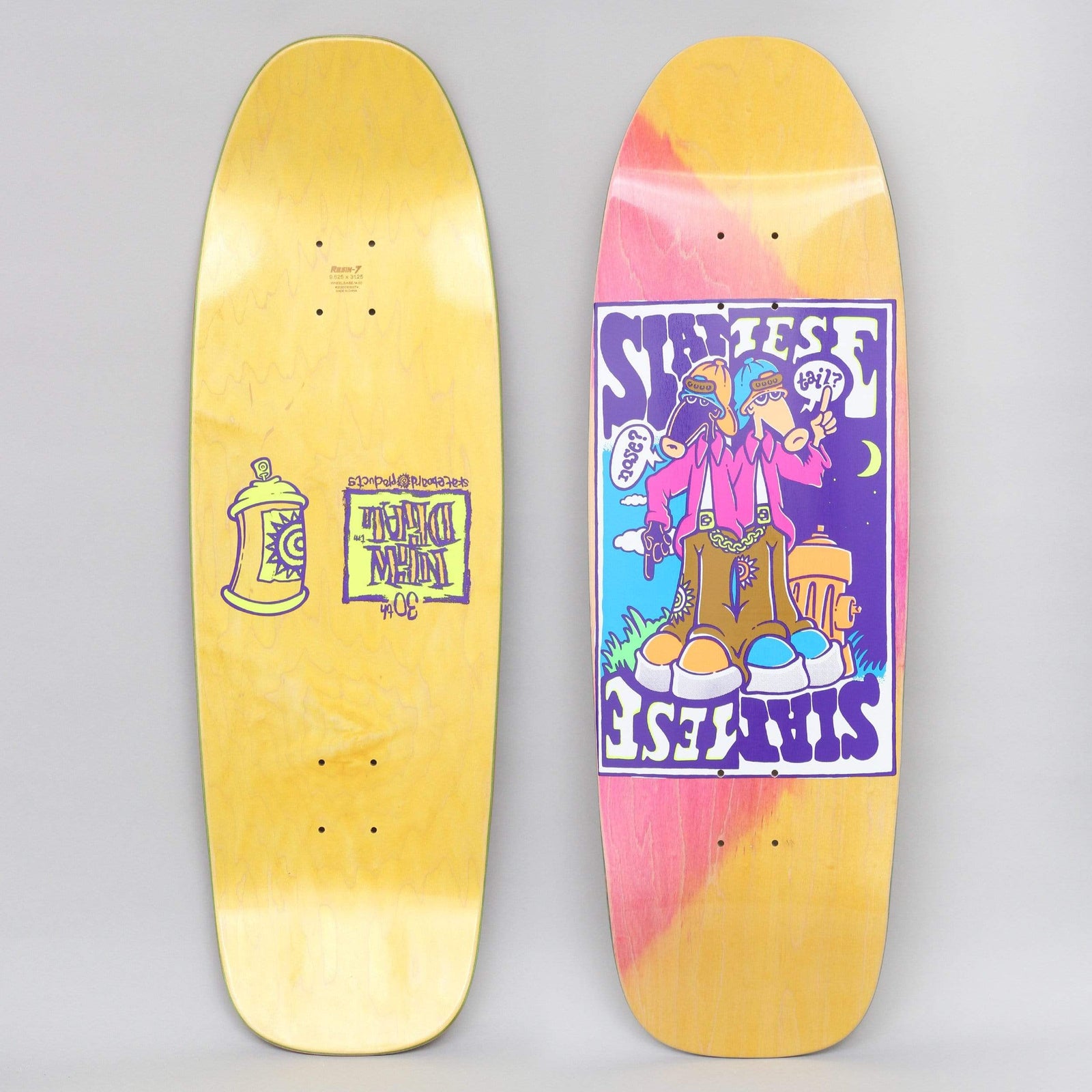 New Deal Siamese Double Kick Neon skateboard deck: Old-school shaped deck with a pink stained top and a purple-bordered panel showing two-headed cartoon Siamese twin figure in pink jacket, chains and big boots by a hydrant, with speech bubbles. Yellow underside with a spray can.