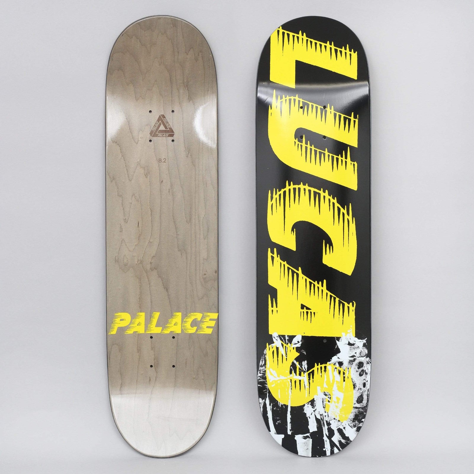 Palace Lucas S21 skateboard deck: Black deck with large yellow dripping, spiky lettering reading 'LUCAS' running down it, over a distressed black and white photographic image at the bottom. The underside has a yellow Palace logo.