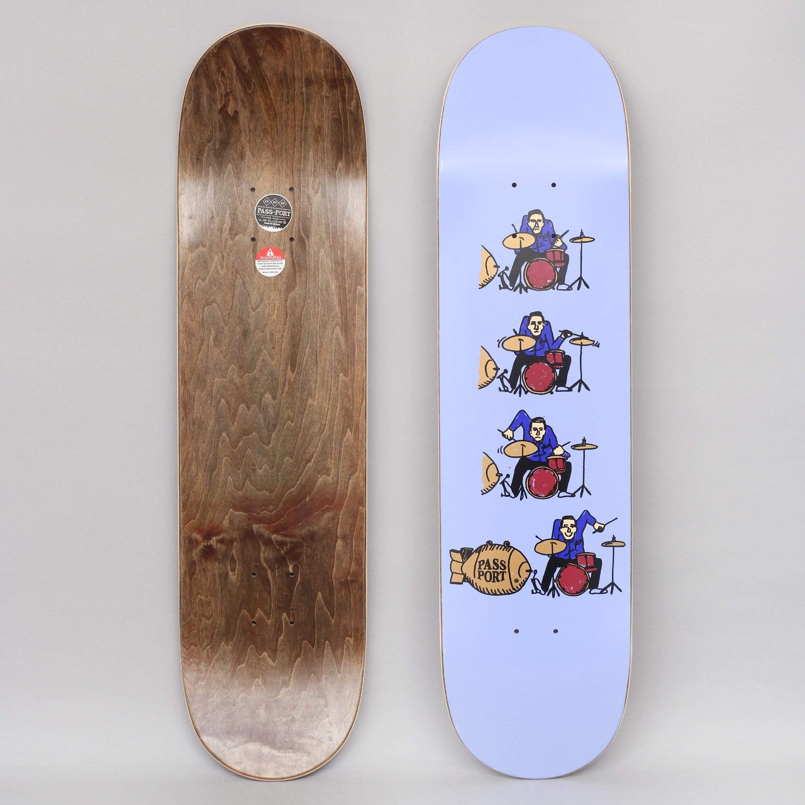 Passport What U Thought Series Drums Purple skateboard deck: Four stacked cartoon drummers in blue shirts playing red drum kits, each with a gold bomb shaped like a barrel, the bottom one marked PASS PORT, on a lavender deck.
