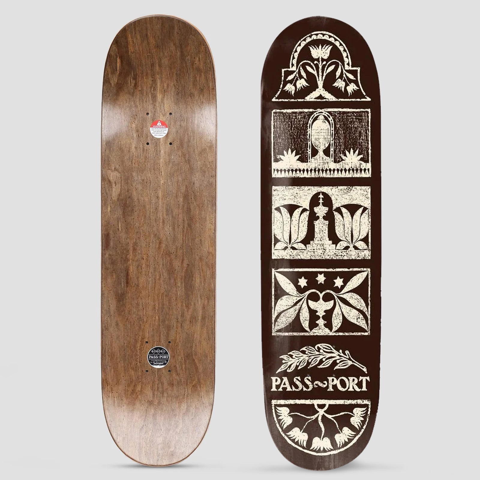 Passport Rubbings Series Back Yard skateboard deck: Cream block-print style panels on a dark brown deck, stacked down the board and showing tulips, leaves, a fountain, an urn and stars, with a laurel sprig above the Pass~Port name. The photo also shows the wood underside.