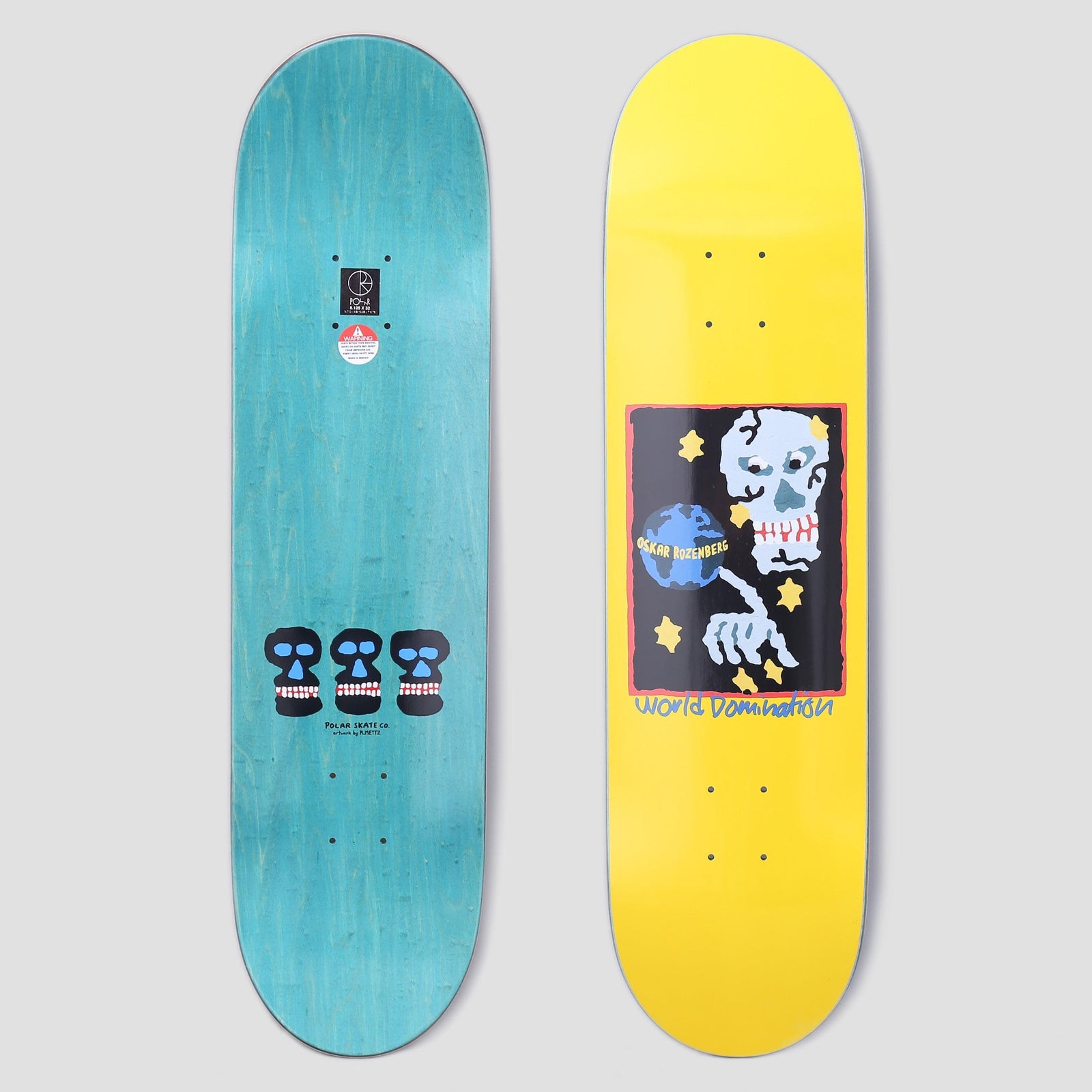 Polar Oski World Domination Yellow skateboard deck: A framed painting-style picture of a pale blue skull pointing at a small globe among yellow stars, with World Domination handwritten below, on a yellow deck. The underside shows three black skulls on teal.