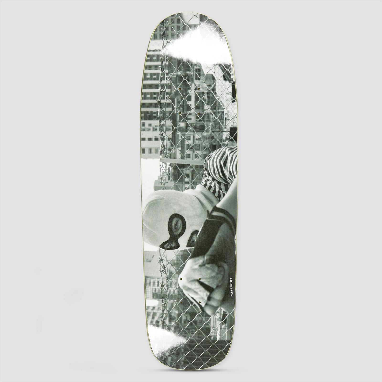 Polar P9 SHAPE Klez Zawisza Hong Kong skateboard deck: Black and white photograph of a person in a balaclava and striped sleeve leaning on a chain-link fence with barbed wire, tall city buildings behind, with white spray marks at both ends. Rider name in tiny type.