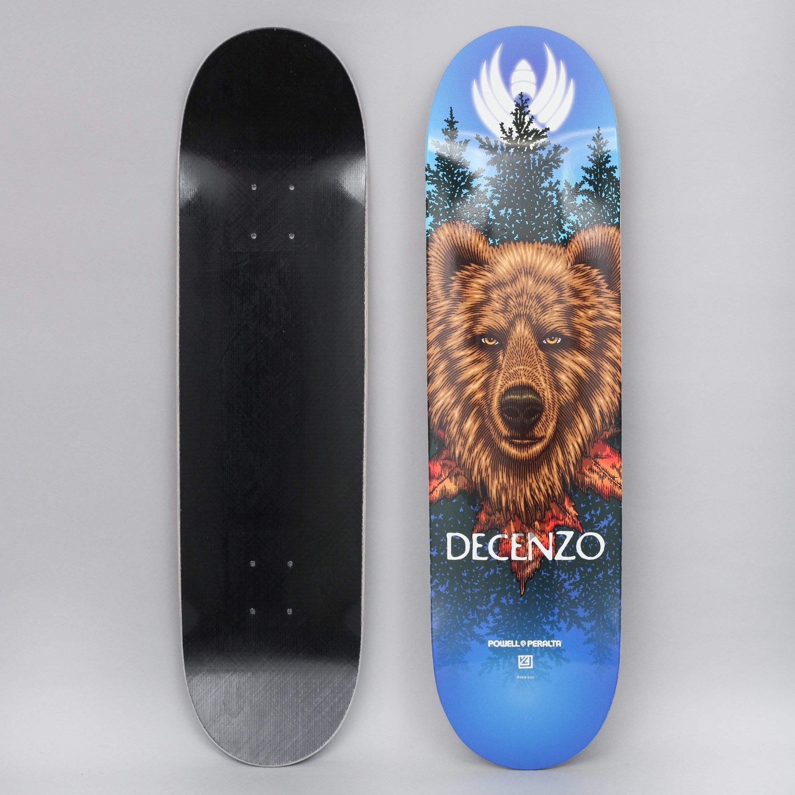 Powell Peralta Peralta 8.25 Scott Decenzo Bear Shape 248 Flight skateboard deck: Detailed illustration of a brown bear's head facing forward among pine trees and red leaves, with a white winged emblem glowing at the top, on a blue gradient. DECENZO in white lettering below.