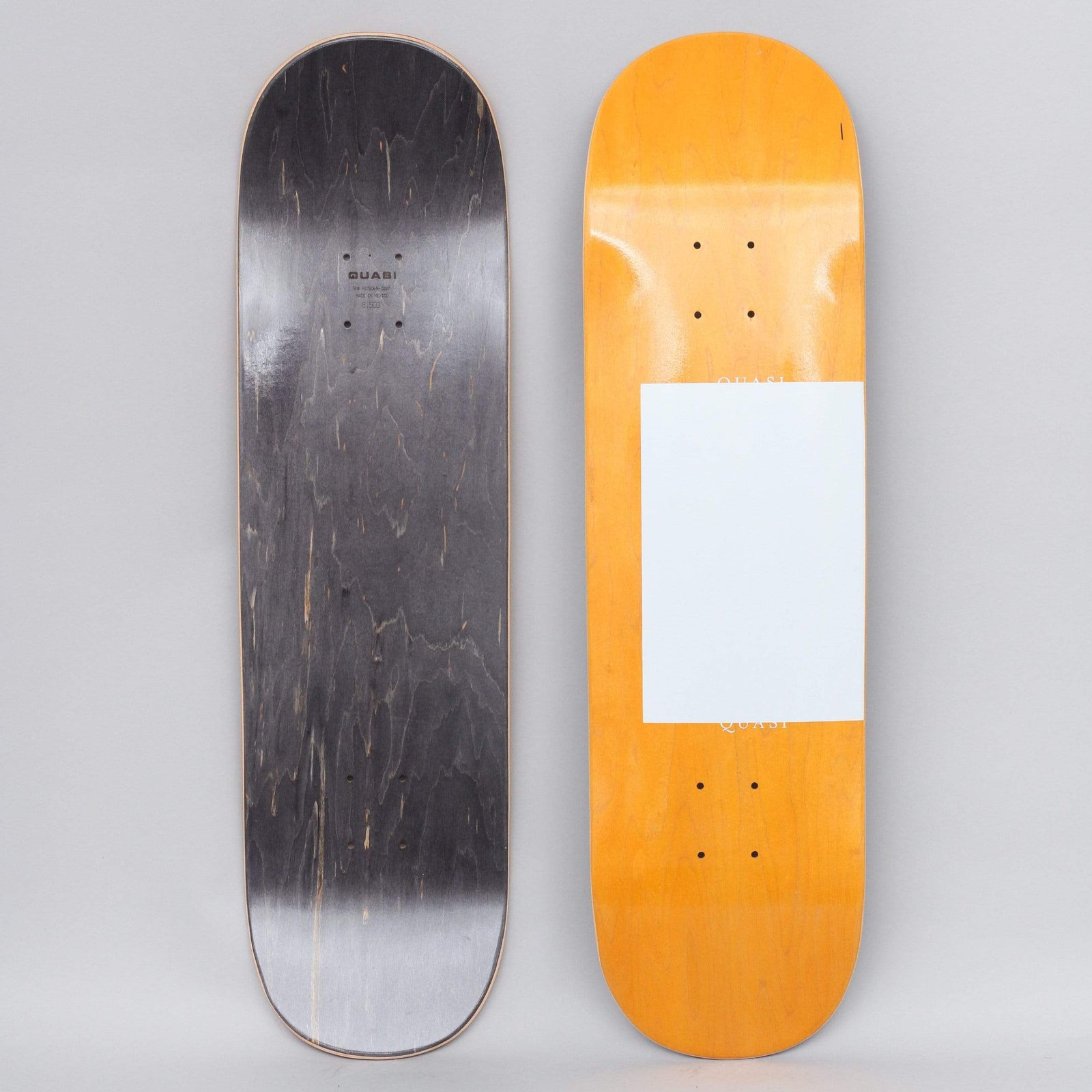 Quasi Quasi 8.5 Proto skateboard deck: Minimal design of a plain white rectangle with small QUASI text at its top and bottom edges, set on an orange-stained wood deck. The underside is stained black with a small logo.