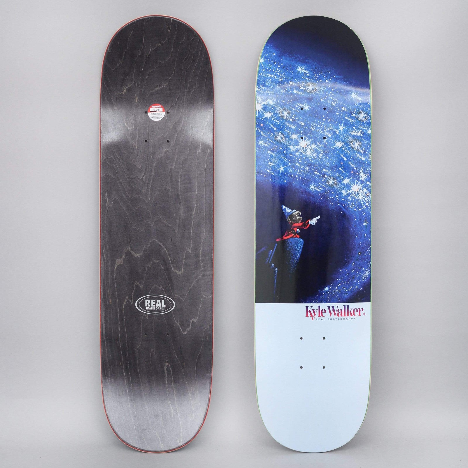 Real Kyle Sorcerer skateboard deck: Cartoon sorcerer's apprentice in a pointed hat and red robe stands on a rock, pointing at a swirling sky of sparkling blue stars. Rider's name in script on a pale blue lower panel.