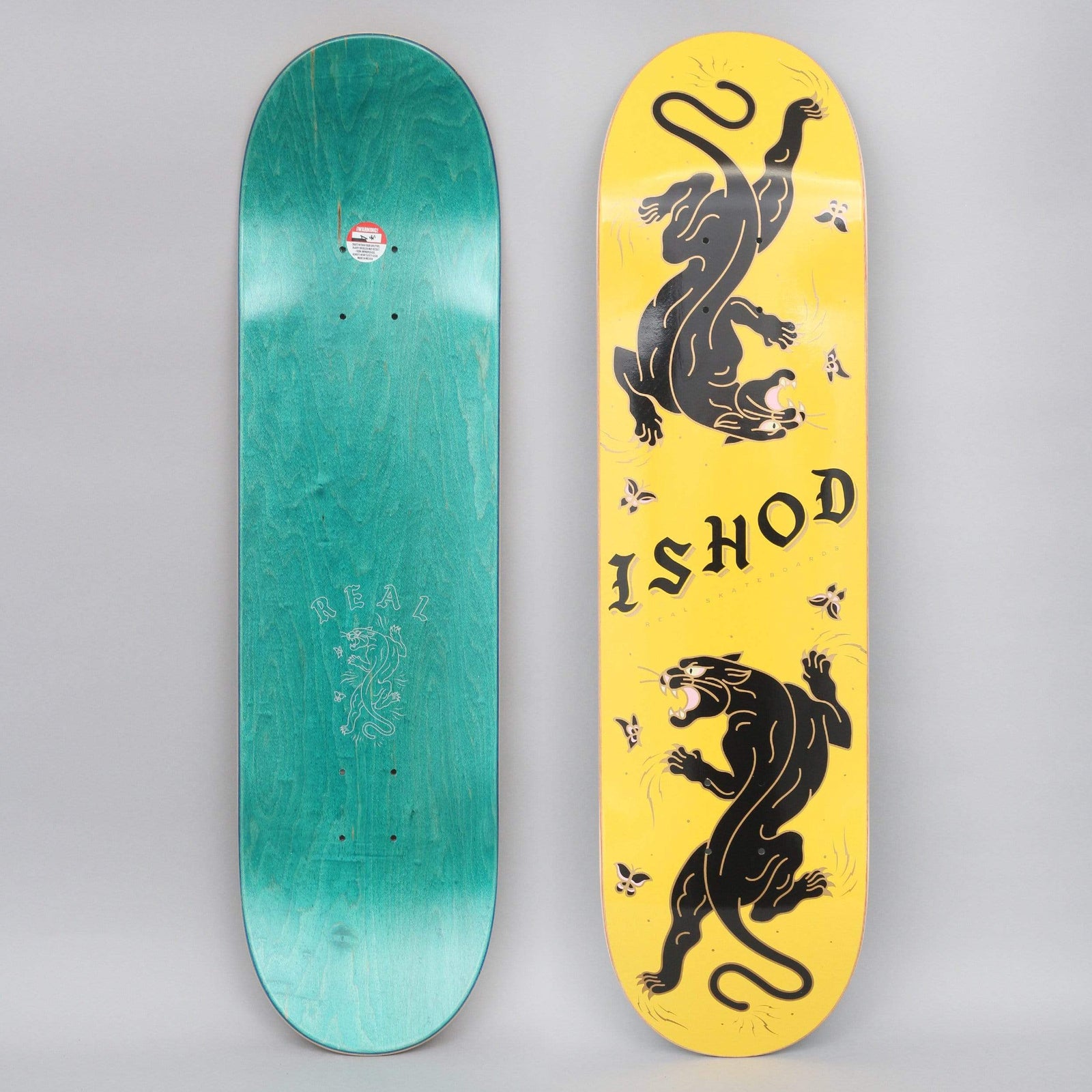 Real Ishod Cat-Scratch TT Yellow / Black skateboard deck: Yellow deck with two black panthers in traditional tattoo style, one climbing down and one prowling up, with small flowers and 'ISHOD' in gothic black lettering between them.