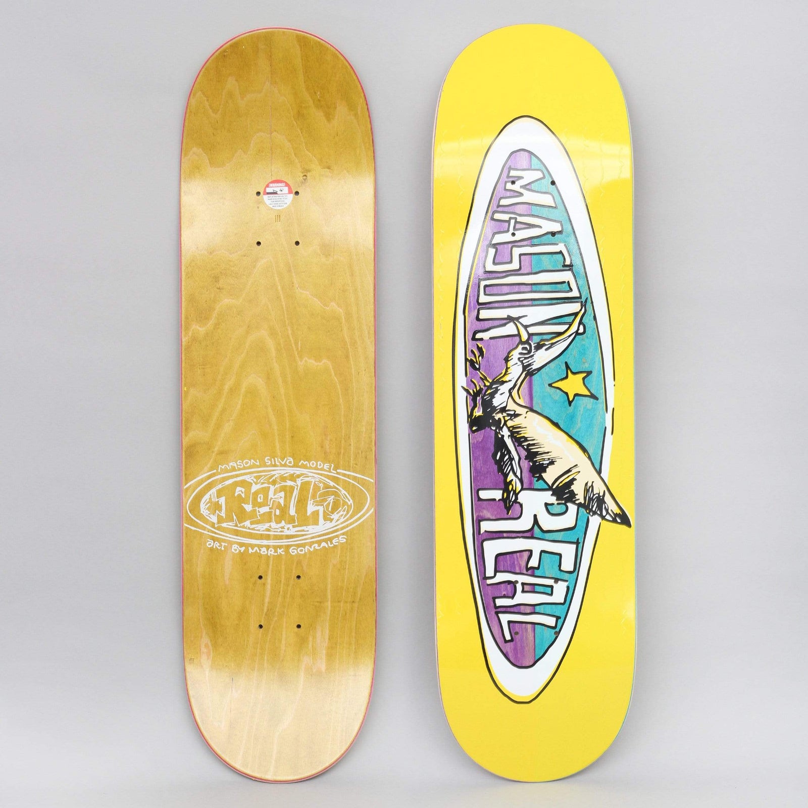 Real Mason Silva Real Bird Oval Yellow skateboard deck: Yellow deck with a long oval badge in purple and teal containing a hand-drawn bird with a long beak and star, with 'Mason' and 'Real' lettering round the edge. The photo also shows the wood underside.