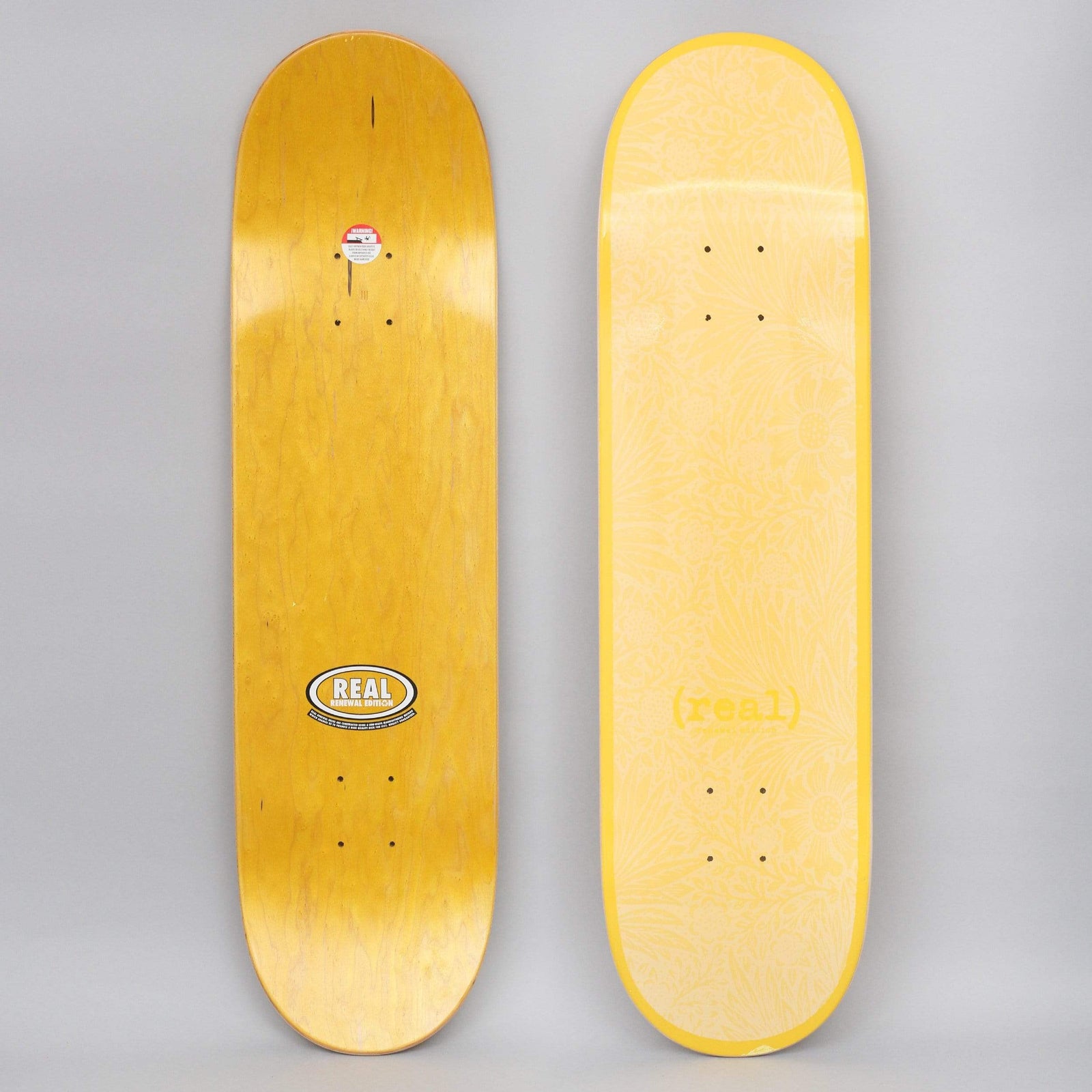 Real Flowers Renewal Yellow skateboard deck: Tone-on-tone yellow deck with a faint floral and foliage pattern and a yellow '(real)' wordmark near the tail. Photo also shows the underside with a Real oval 'Renewal Edition' logo.