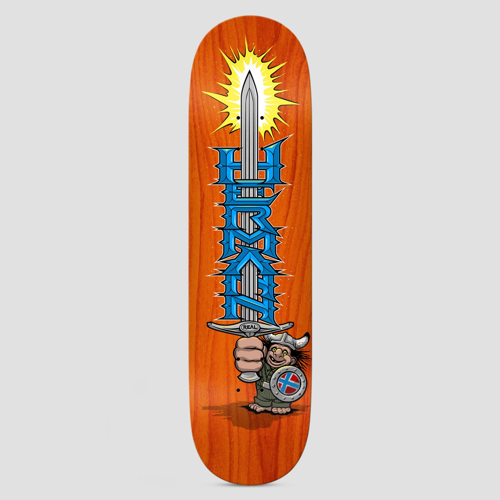 Real Hermann Mighty True Fit skateboard deck: Fist gripping a huge sword with a glowing yellow burst at the tip and blue spiky metal-style 'HERMAN' lettering down the blade. A cartoon troll in a horned helmet with a Norwegian-style shield stands below, on an orange stained deck.