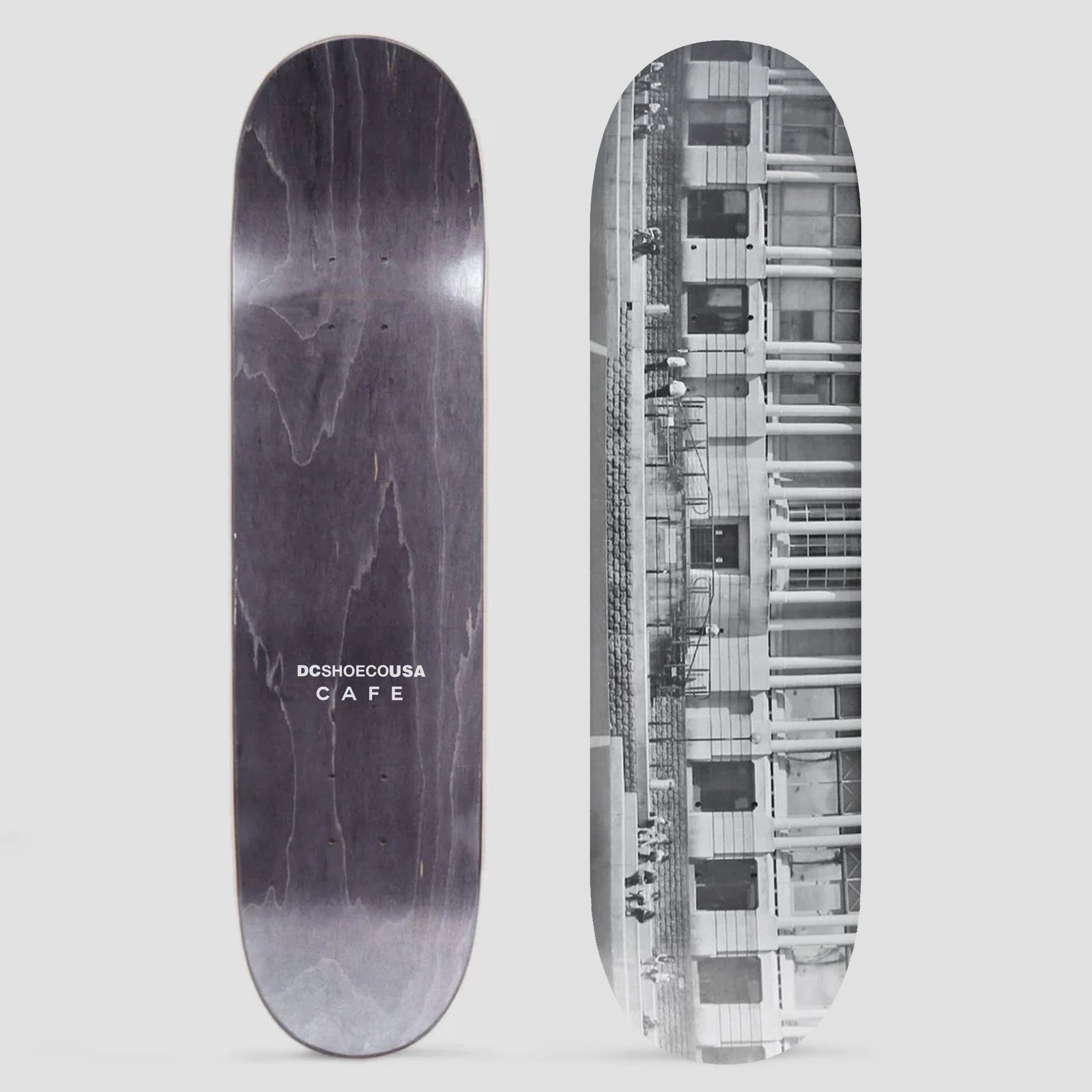 Skateboard Cafe x DC Shoes 8.0 Lloyds Photo Grey skateboard deck: A black and white photograph of a building facade with rows of windows, columns and a fire escape, with a few tiny figures along it. The photo also shows the grey underside with DC Shoe Co USA Cafe text.