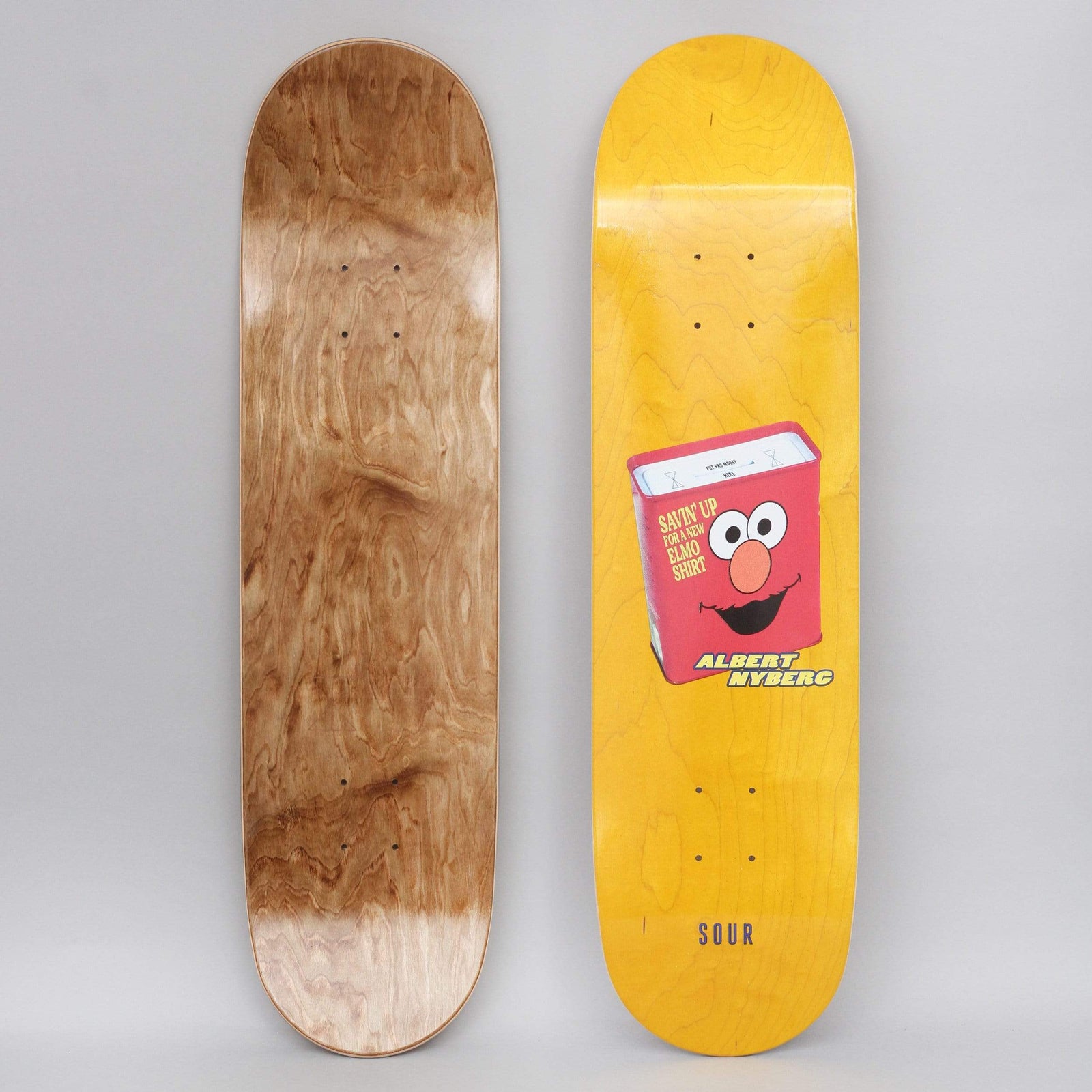 Sour Albert Elmo Savings Yellow skateboard deck: Red money tin with an Elmo face, labelled Savin' up for a new Elmo shirt, with ALBERT NYBERG in yellow lettering below on a yellow-stained deck. SOUR is printed near the tail.